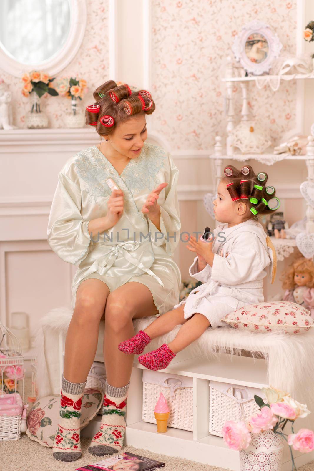 Adorable little girl with her mother in curlers paint their fingernails. Copies mom's behavior. Mom teaches her daughter to take care of herself. Beauty day by Try_my_best