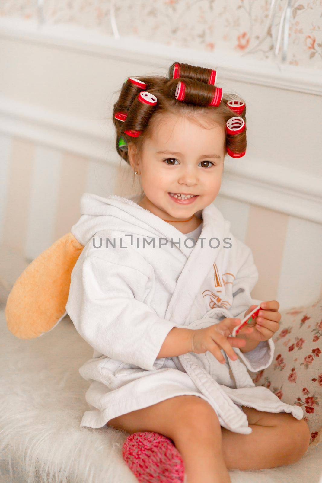 Adorable little girl with curlers paints her fingernails. Copies mom's behavior. Young fashionista. Beauty day by Try_my_best