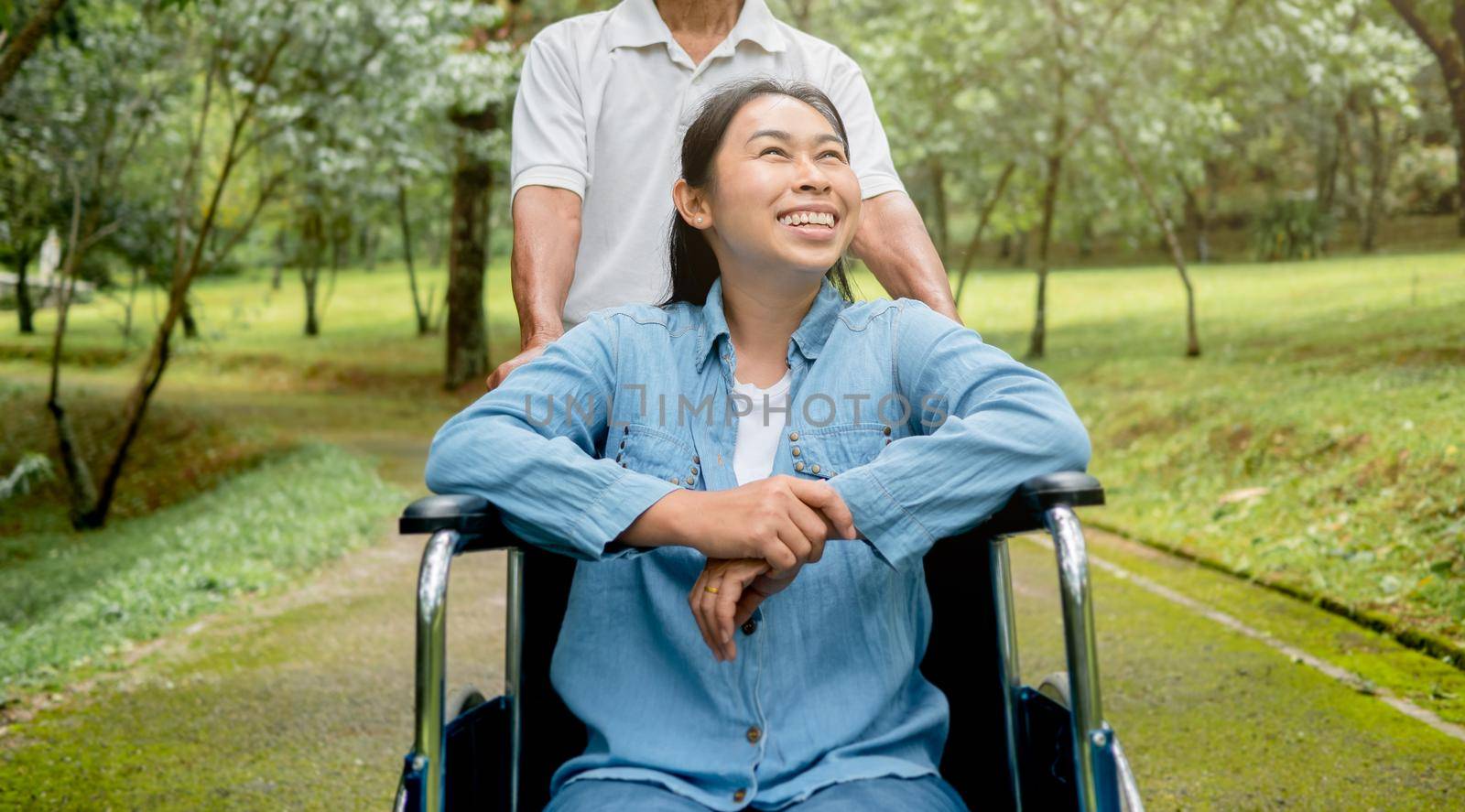 Happy senior man in a wheelchair enjoying nature in the park.