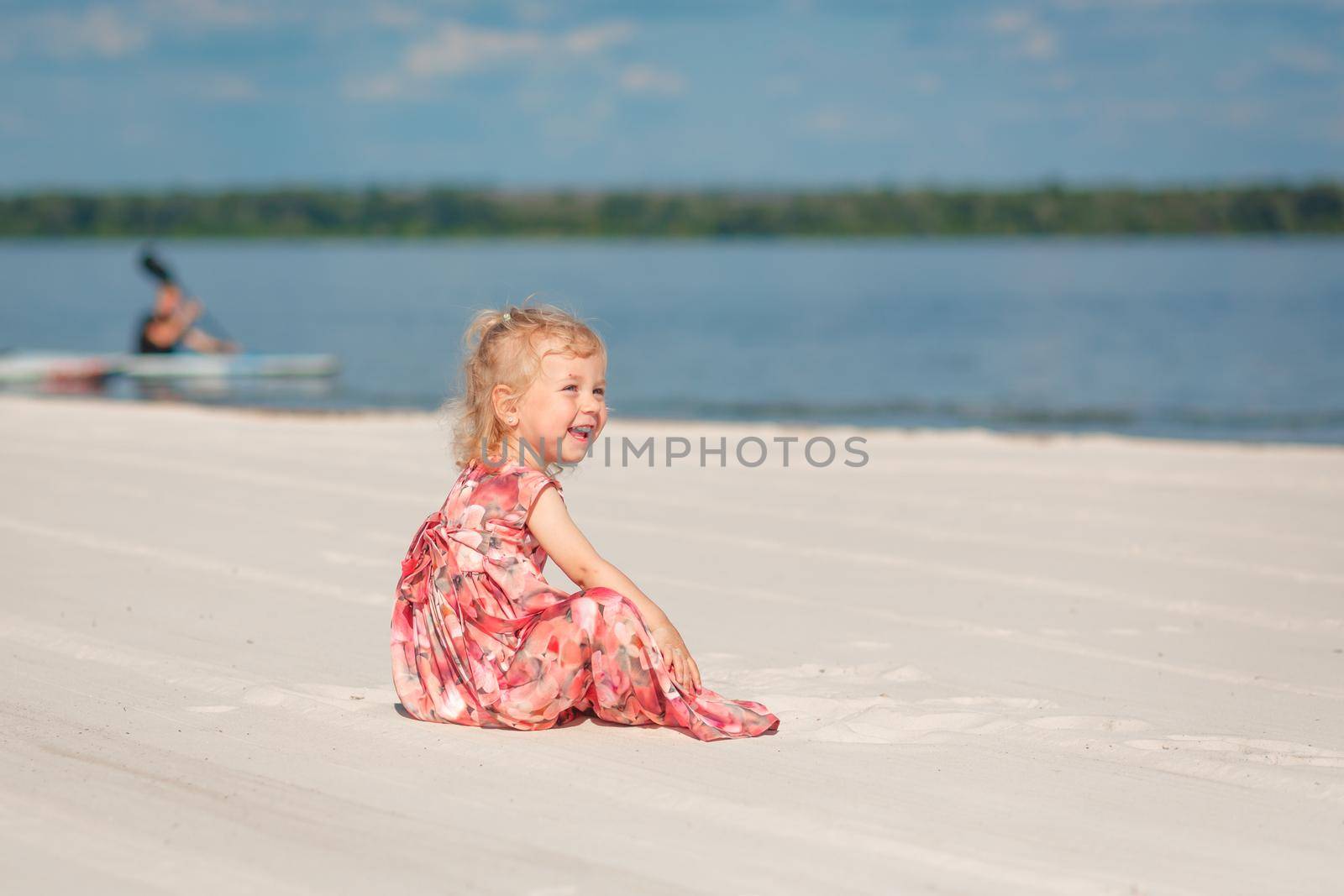 A little girl in a beautiful sarafna plays in the sand on the beach.