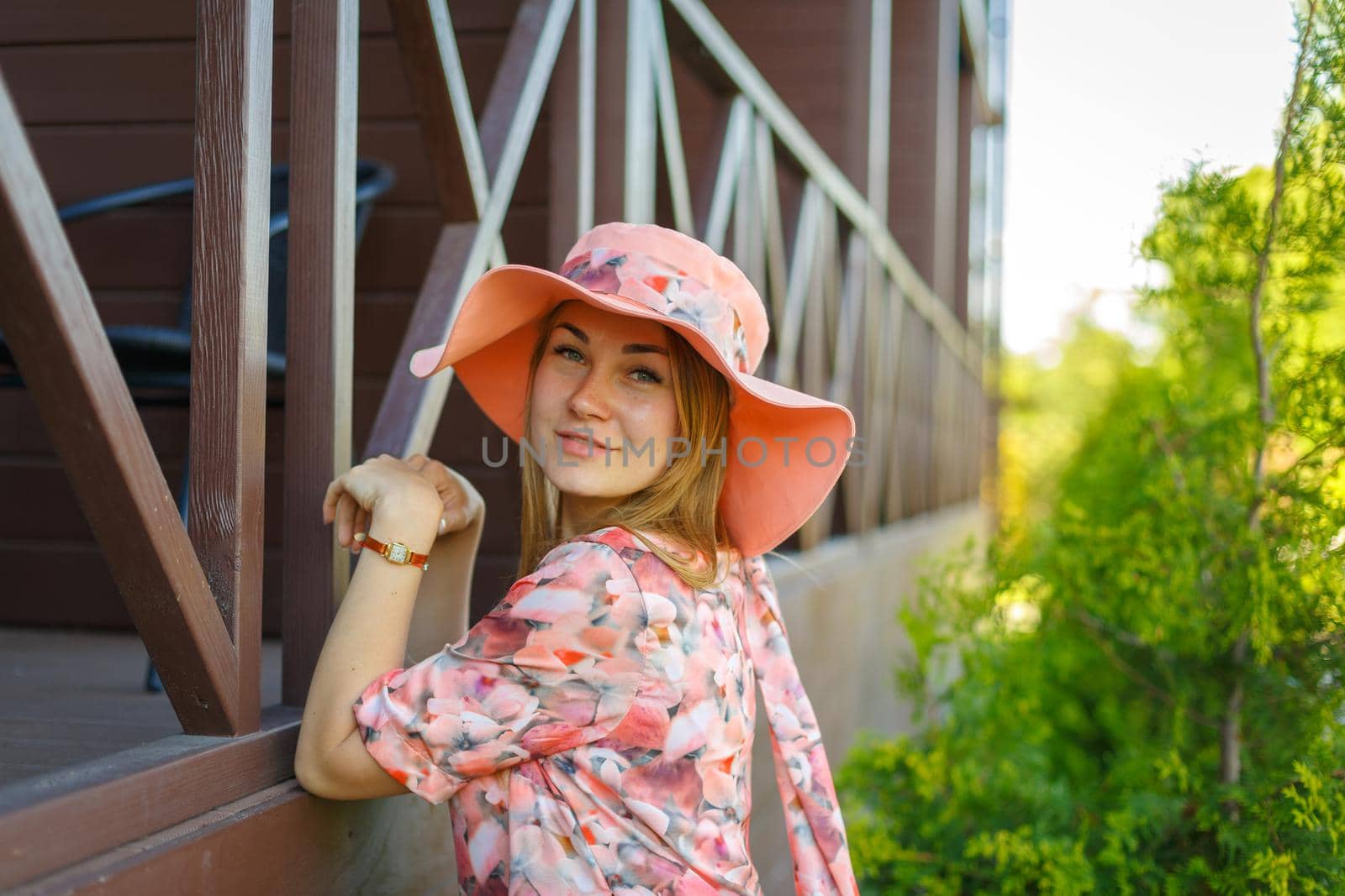 A charming girl in a light summer sundress and a pareo hat is walking in a green park. Enjoys warm sunny summer days by Try_my_best