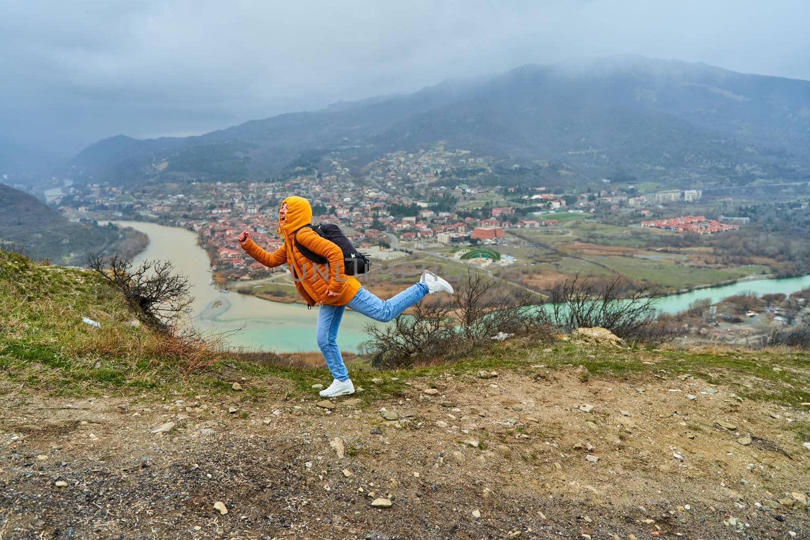 Young girl tourist rejoices posing against the backdrop of an amazing natural landscape. The confluence of two rivers in the city of Mtskheta in Georgia.