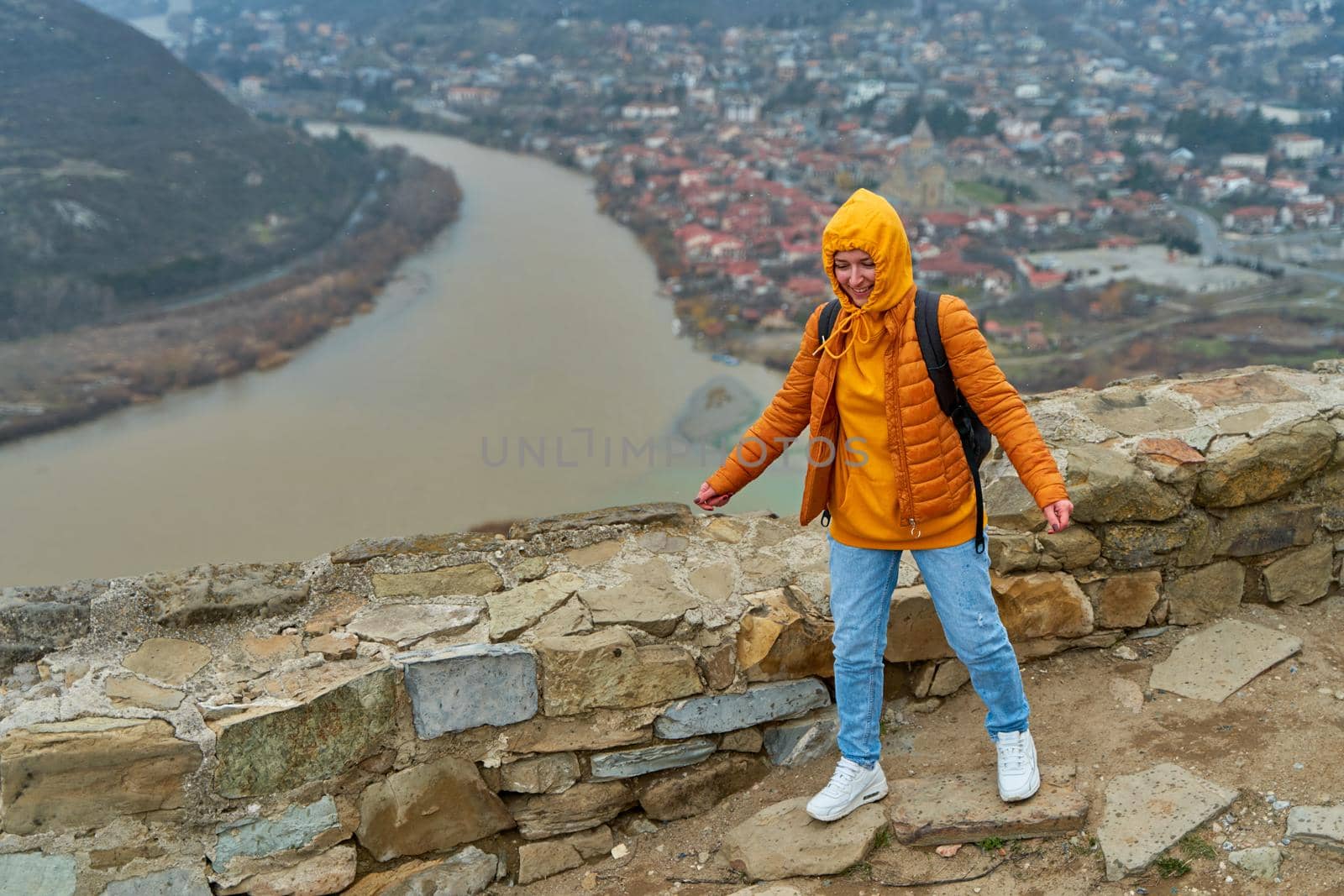 Young girl tourist rejoices posing against the backdrop of an amazing natural landscape. The confluence of two rivers in the city of Mtskheta in Georgia by Try_my_best