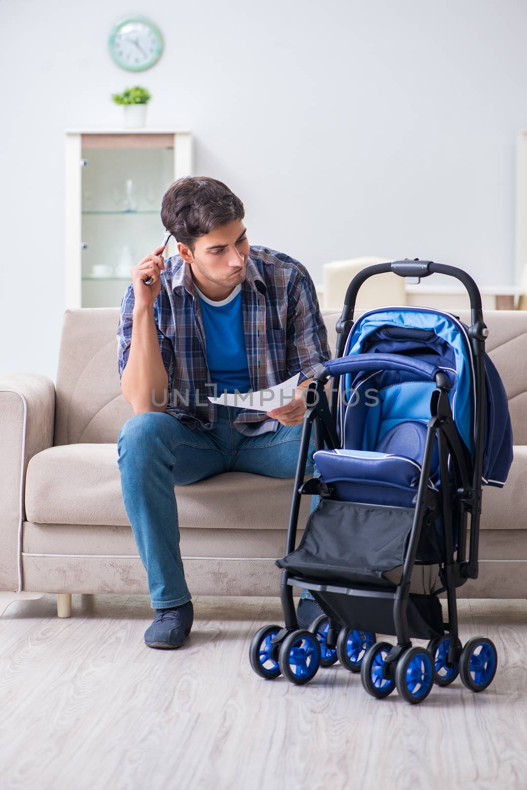 Young father assembling baby pram at home