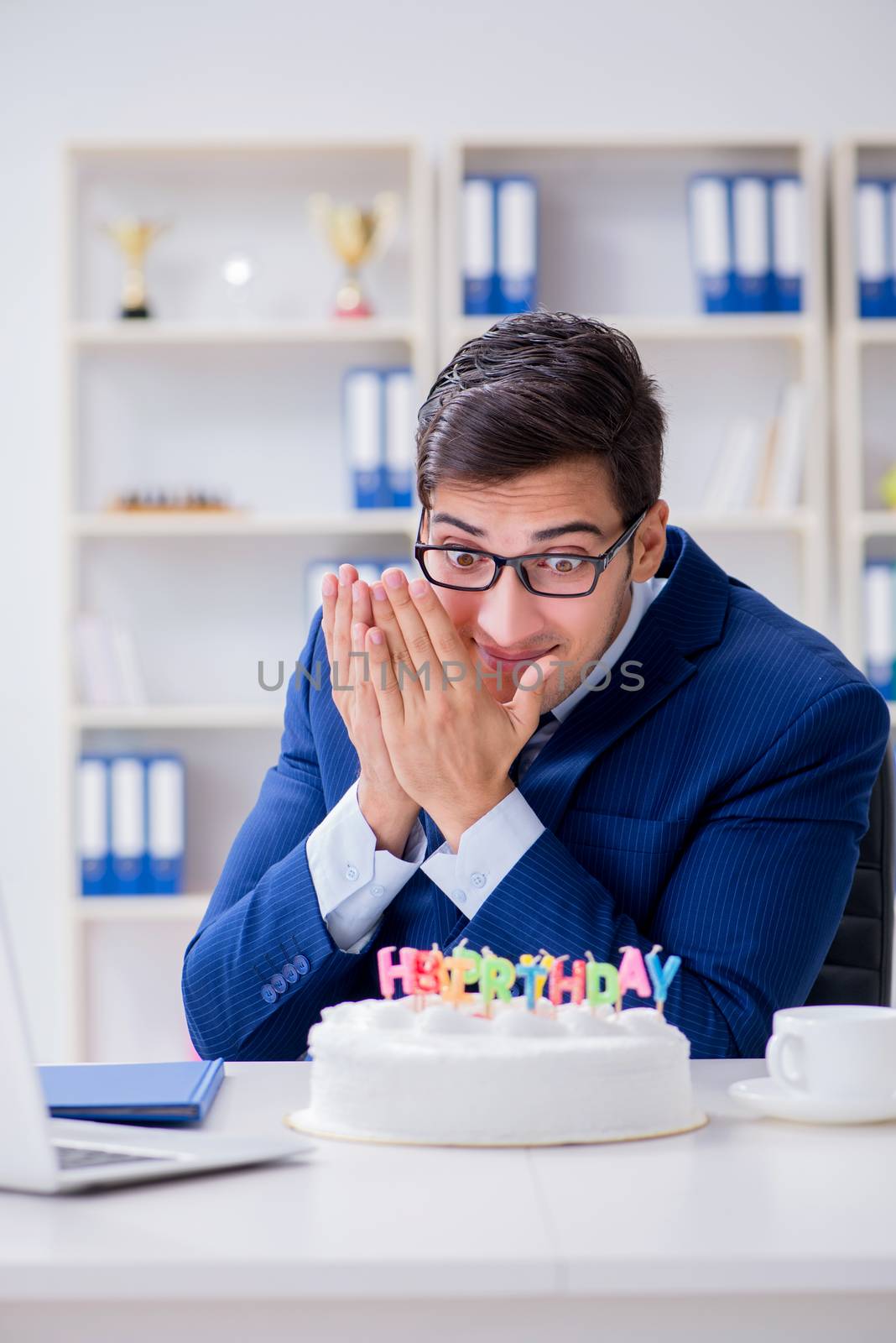 Young businessman celebrating birthday alone in office