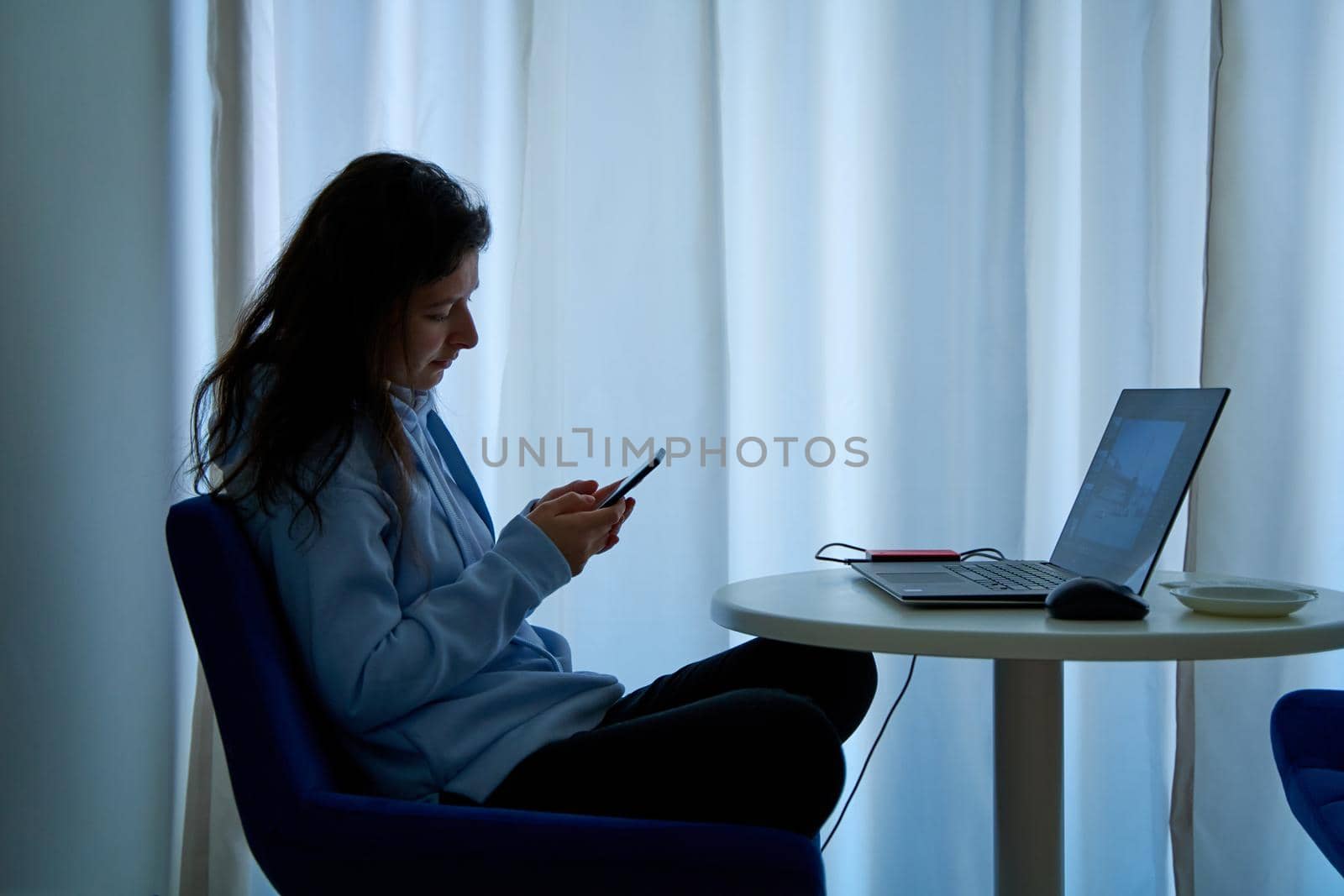 The girl is distracted by the phone at the workplace at the computer.