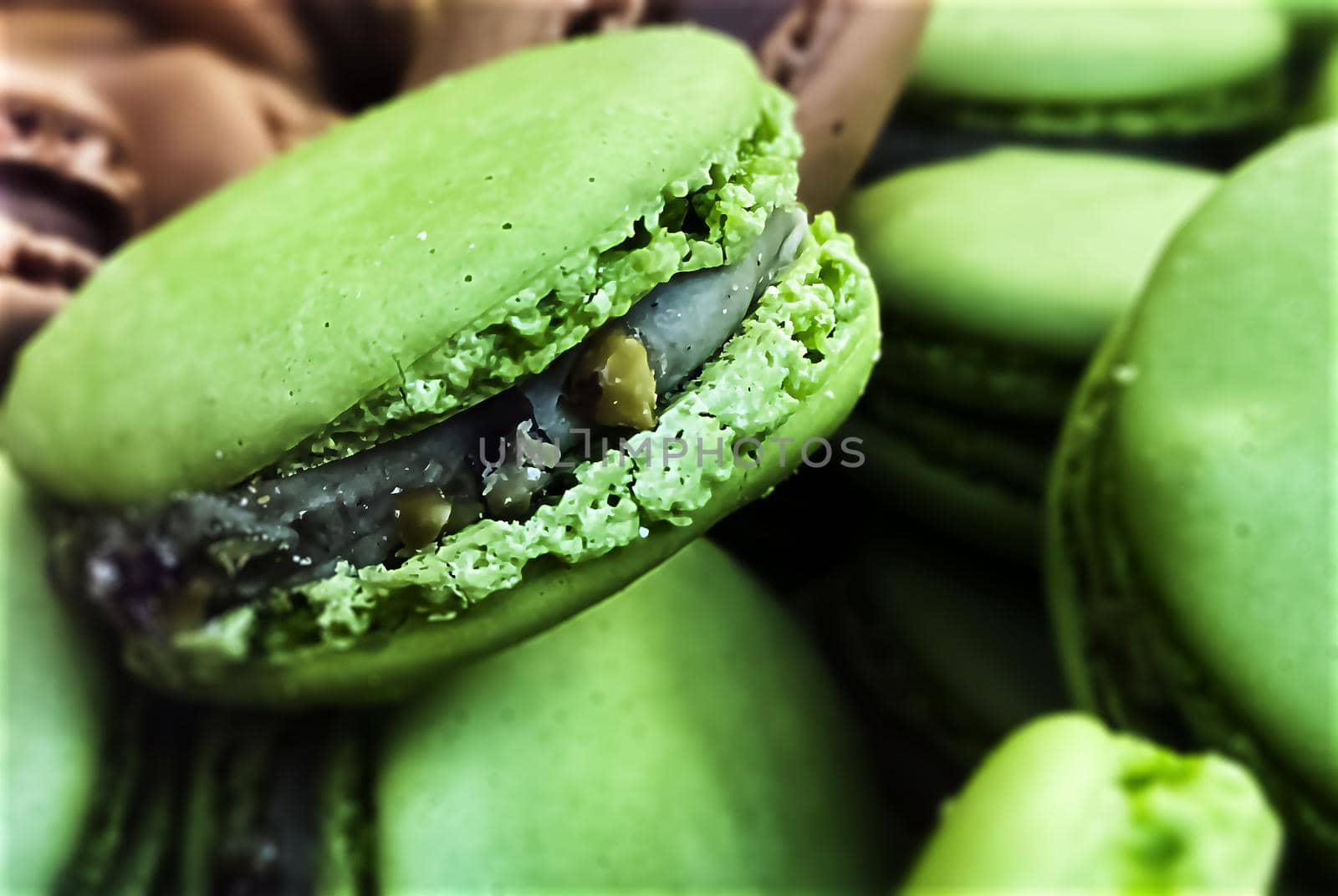 many colorful macaroons biscuits arranged disorderly. In the foreground, the green ones with pistachio flavor. Baked cake with various colors