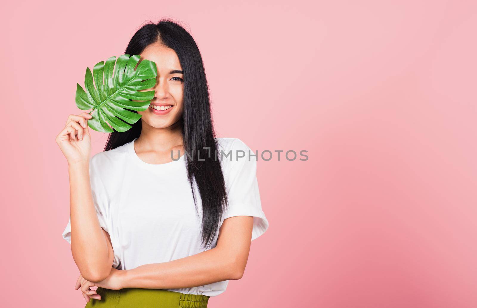 woman with fresh healthy skin hold green monstera leaf on her face by Sorapop