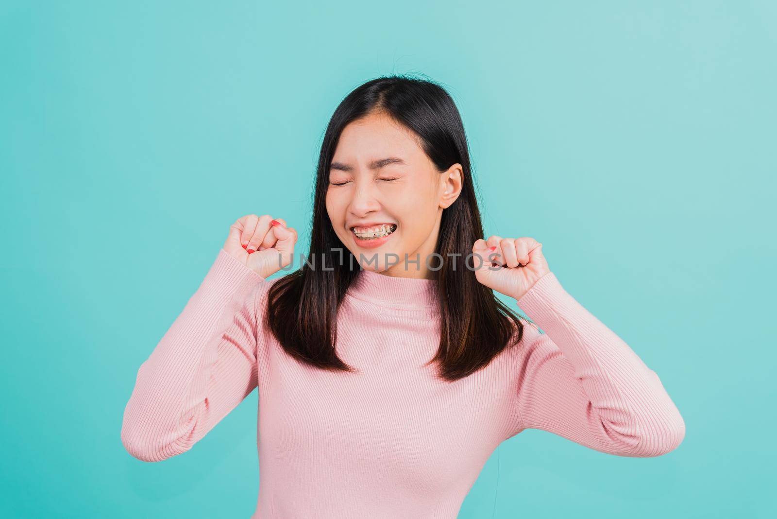 Asian beautiful woman smiling wear silicone orthodontic retainers on teeth surprised she is excited screaming and raise hand make gestures wow by Sorapop