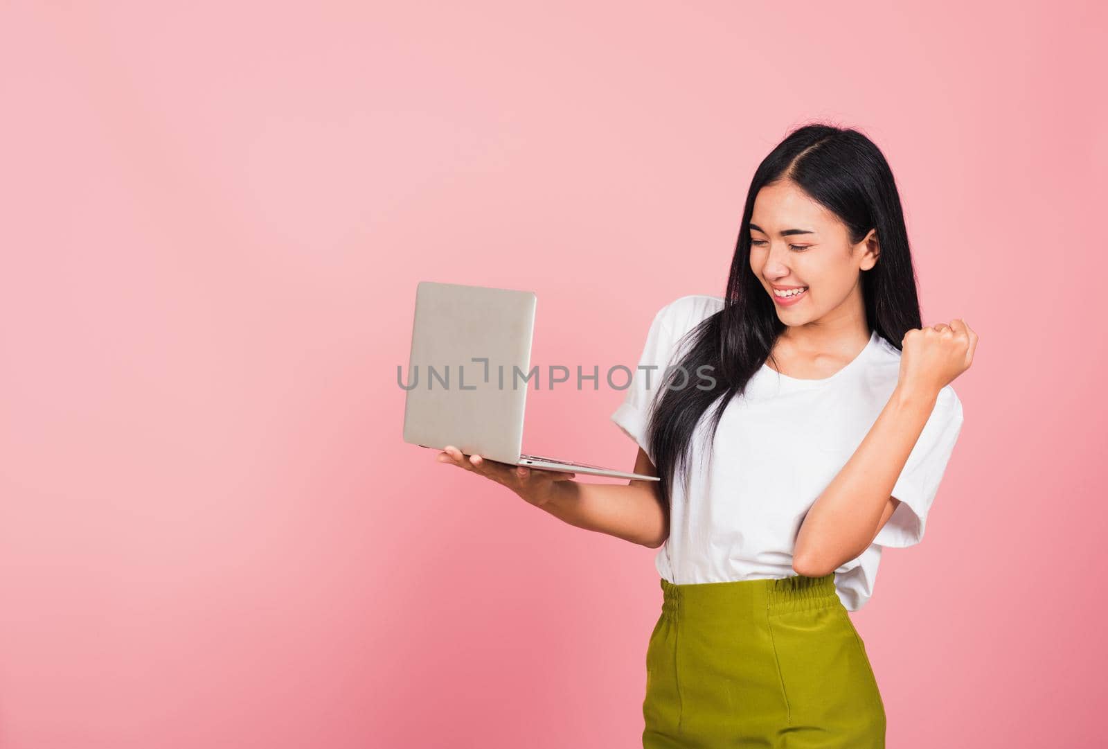 woman teen confident smiling face holding using laptop computer and excited celebrating by Sorapop