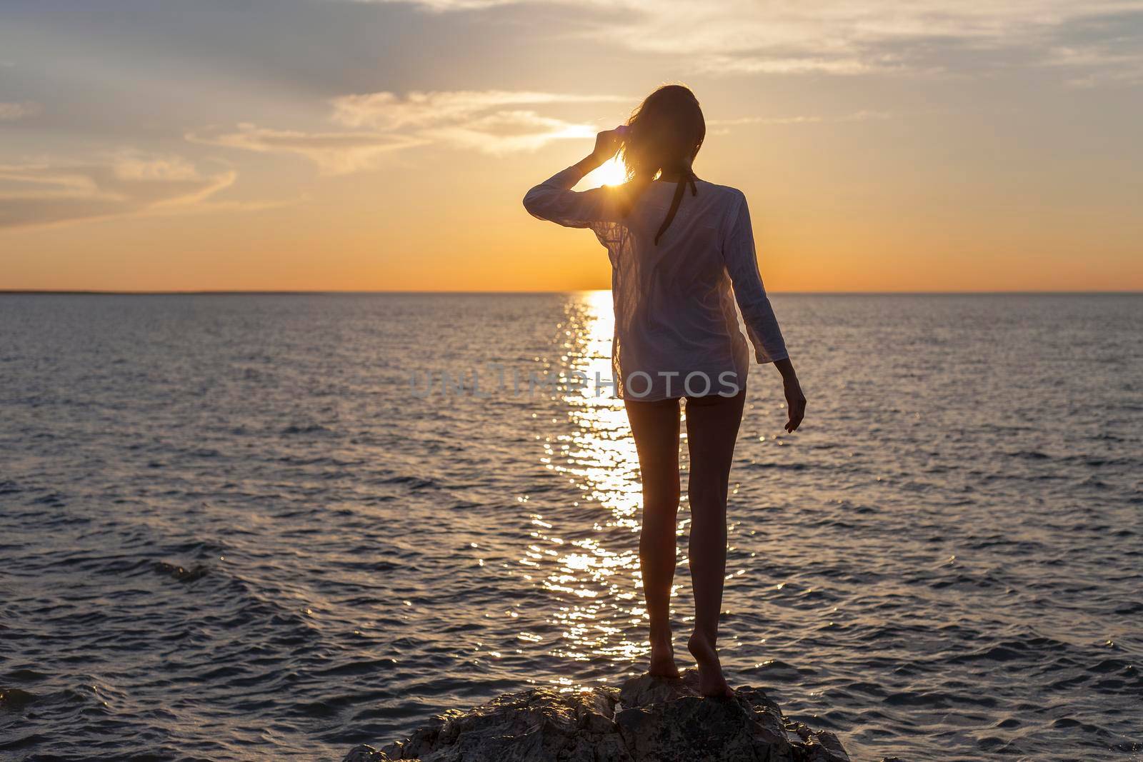 Silhouette of young happy carefree woman posing on the beach at sunset