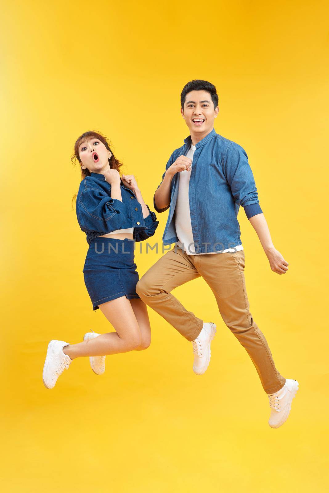 Full length body size photo funky she her he him his pair jumping high raised fists yell scream shout loud wear casual jeans denim white t-shirts isolated yellow background