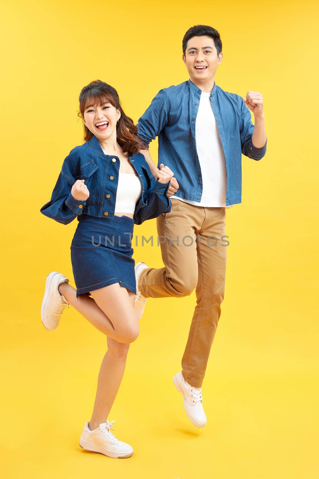 Full length body size view of his he her she nice attractive crazy funky cheerful couple jumping in air having fun fooling rejoicing isolated on yellow by makidotvn