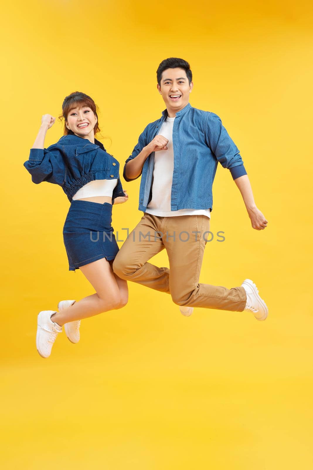 Full length body size view of nice attractive lovely cheerful cheery couple jumping up in air isolated over yellow background