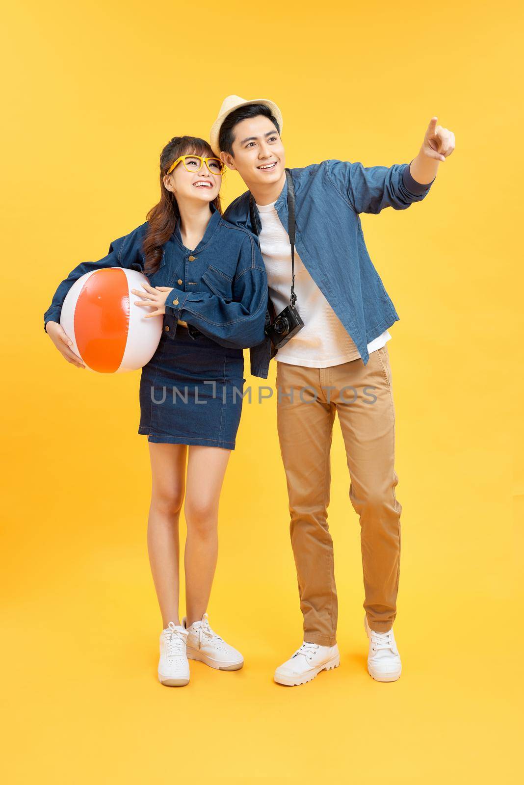 Happy Asian couple in summer beach casual clothes studio shot isolated on yellow banner background with copy space