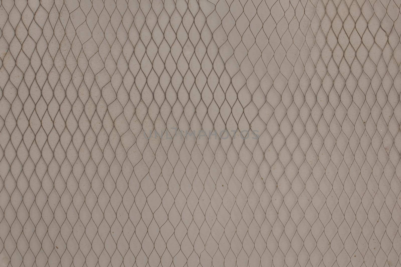 metal net on dirty light grey wall to prevent posting of paper advertisements, background and texture.