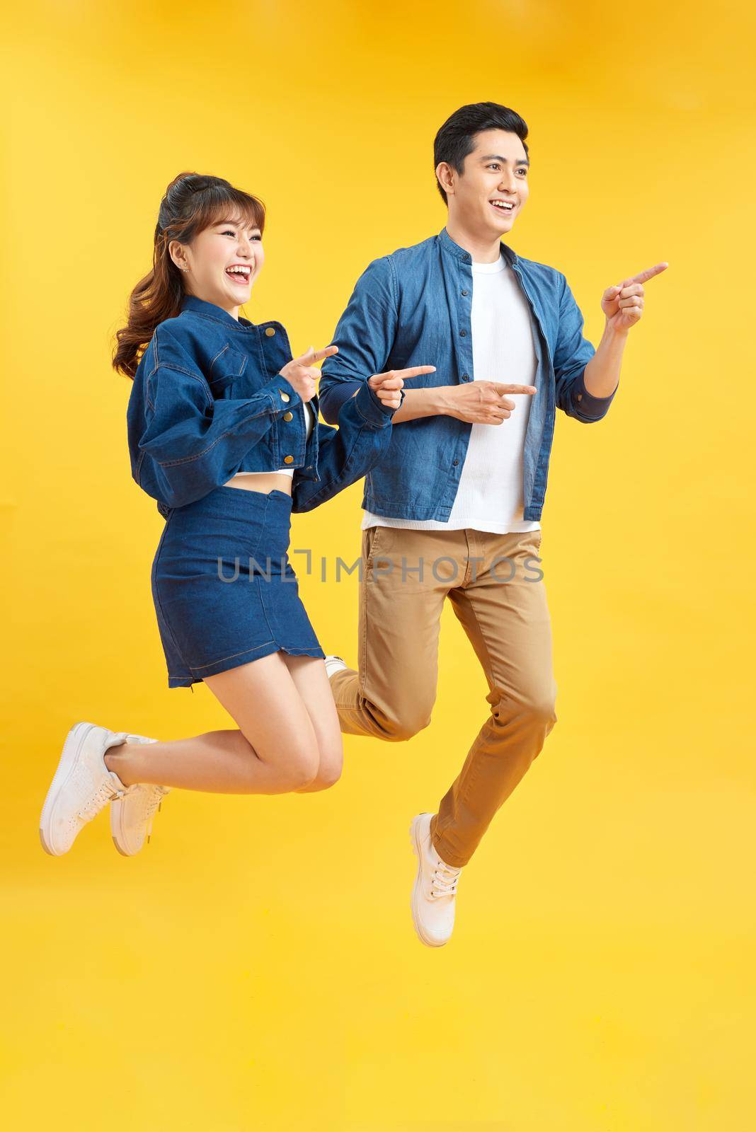 Full length body size view of his he her she nice attractive crazy funky cheerful couple jumping in air having fun fooling rejoicing isolated on yellow by makidotvn