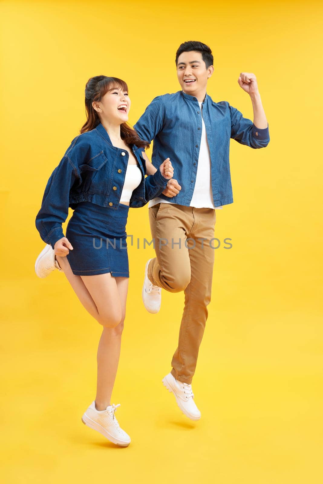 Full length body size view of nice attractive lovely cheerful cheery couple jumping up in air isolated over yellow background