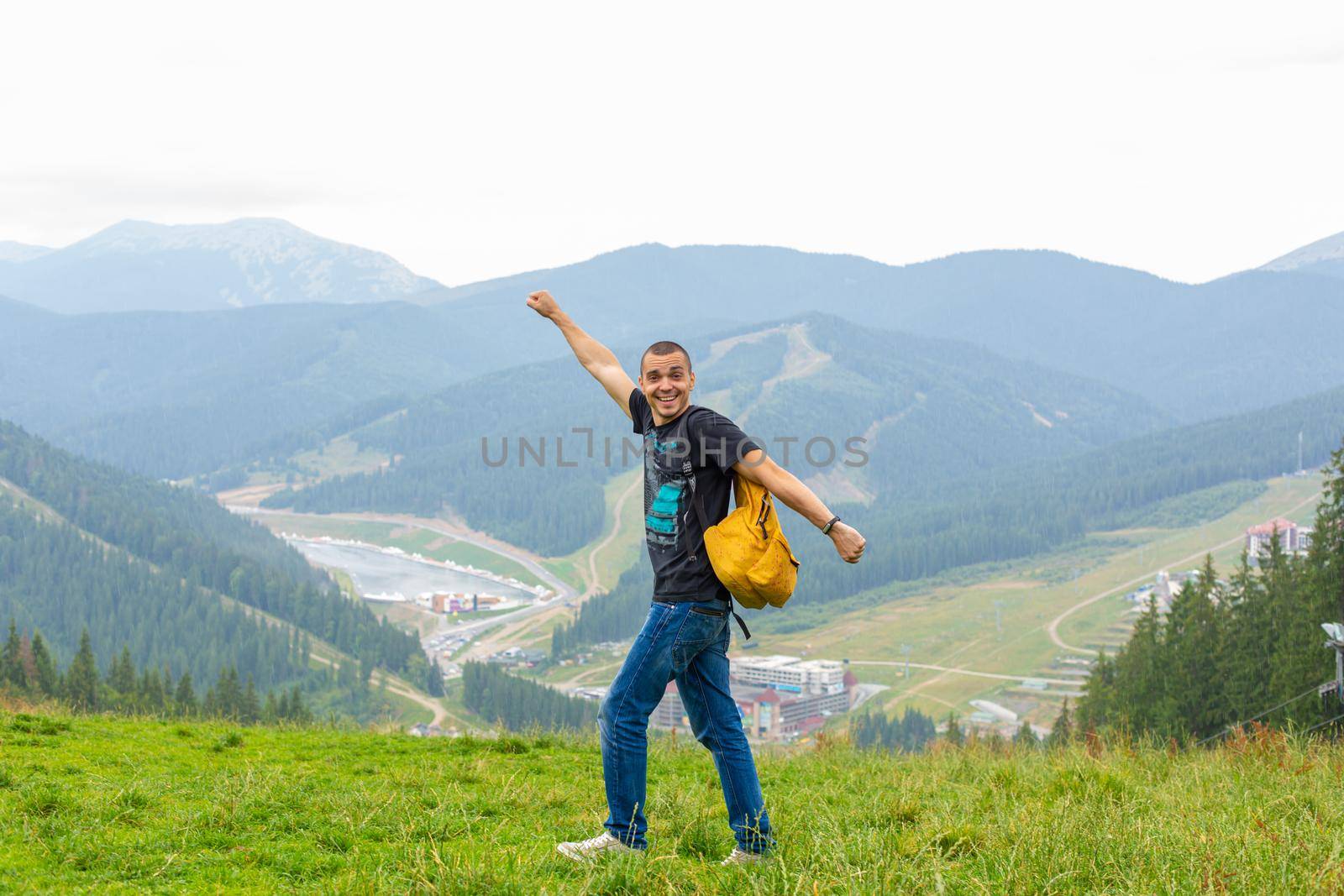 A guy travels with a yellow backpack through picturesque places with beautiful mountain landscapes.