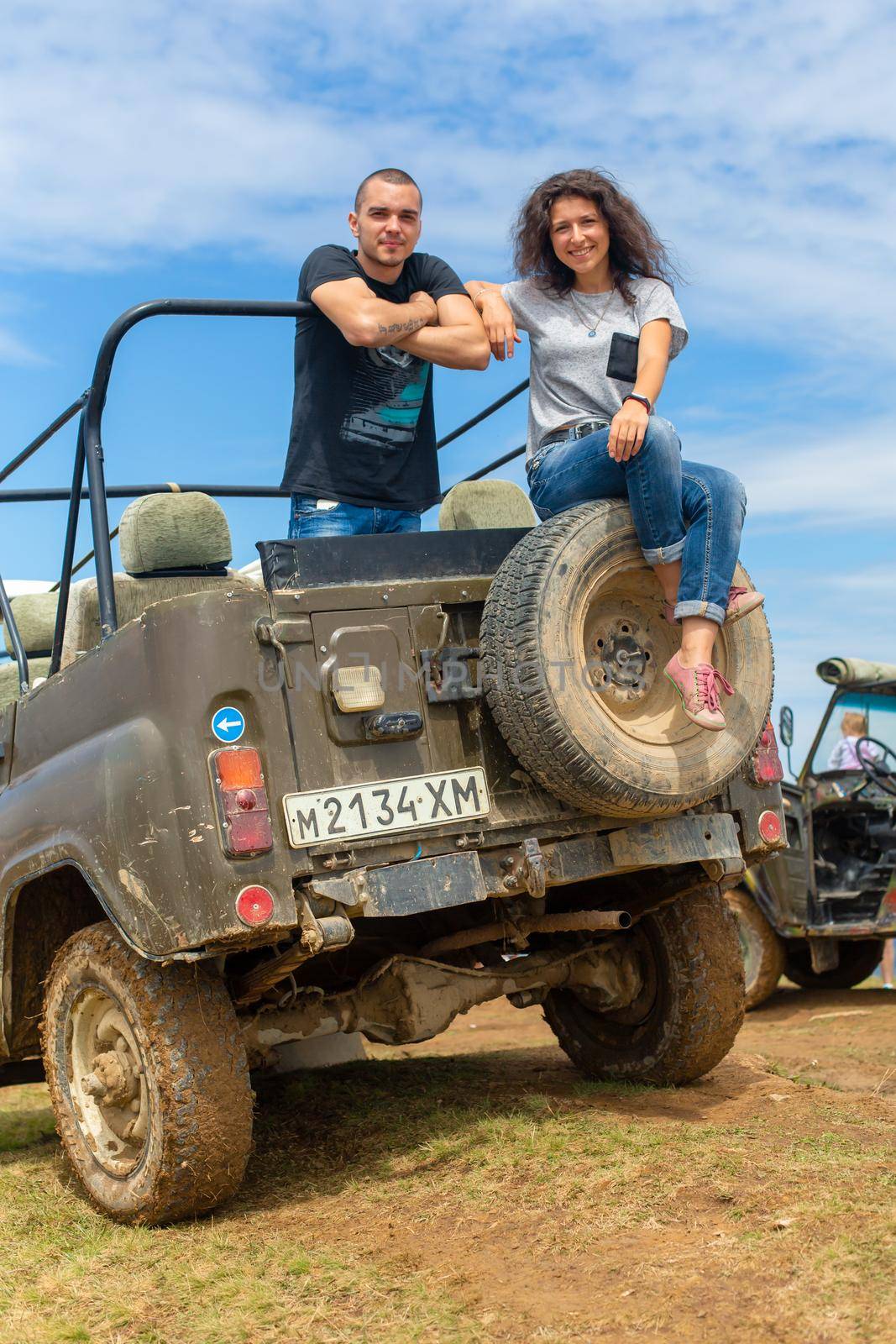 Happy young couple resting on the dirty offroad car. Highland car tour by Try_my_best