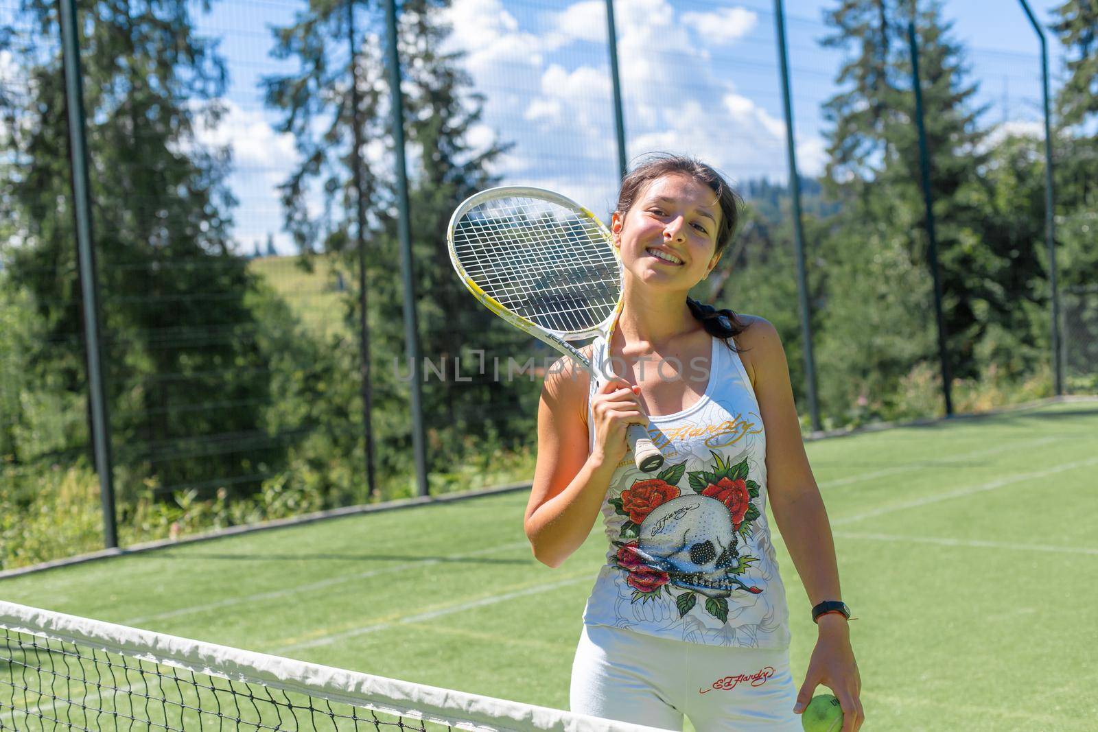 Slim gorgeous girl ready to play in tennis on court in bright summer day.