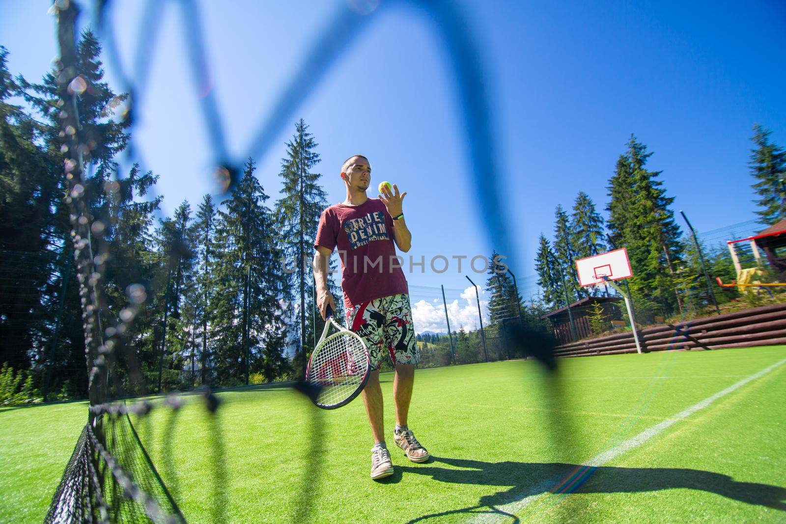 Guy plays in tennis on court in bright summer day.