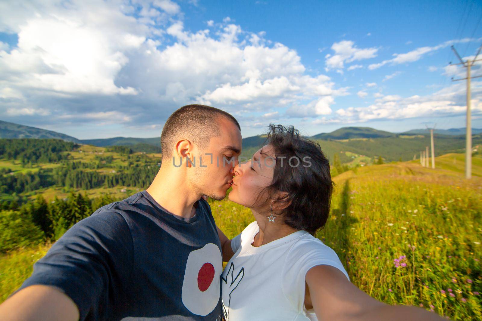 Young couple hugs and take selfie with amazing mountain landscape background by Try_my_best