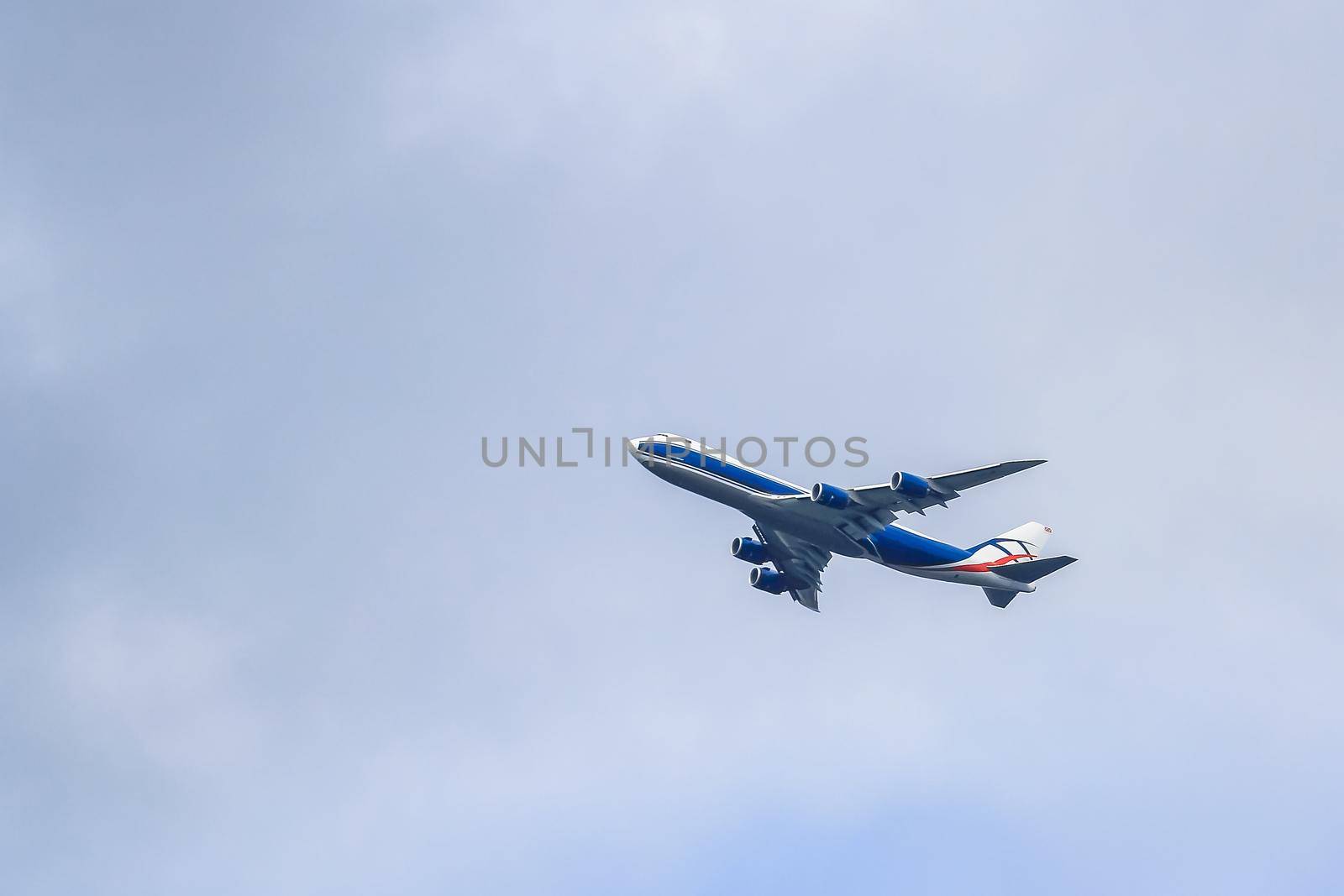 A large passenger plane makes a daily flight in the sky. The sky is clouded over