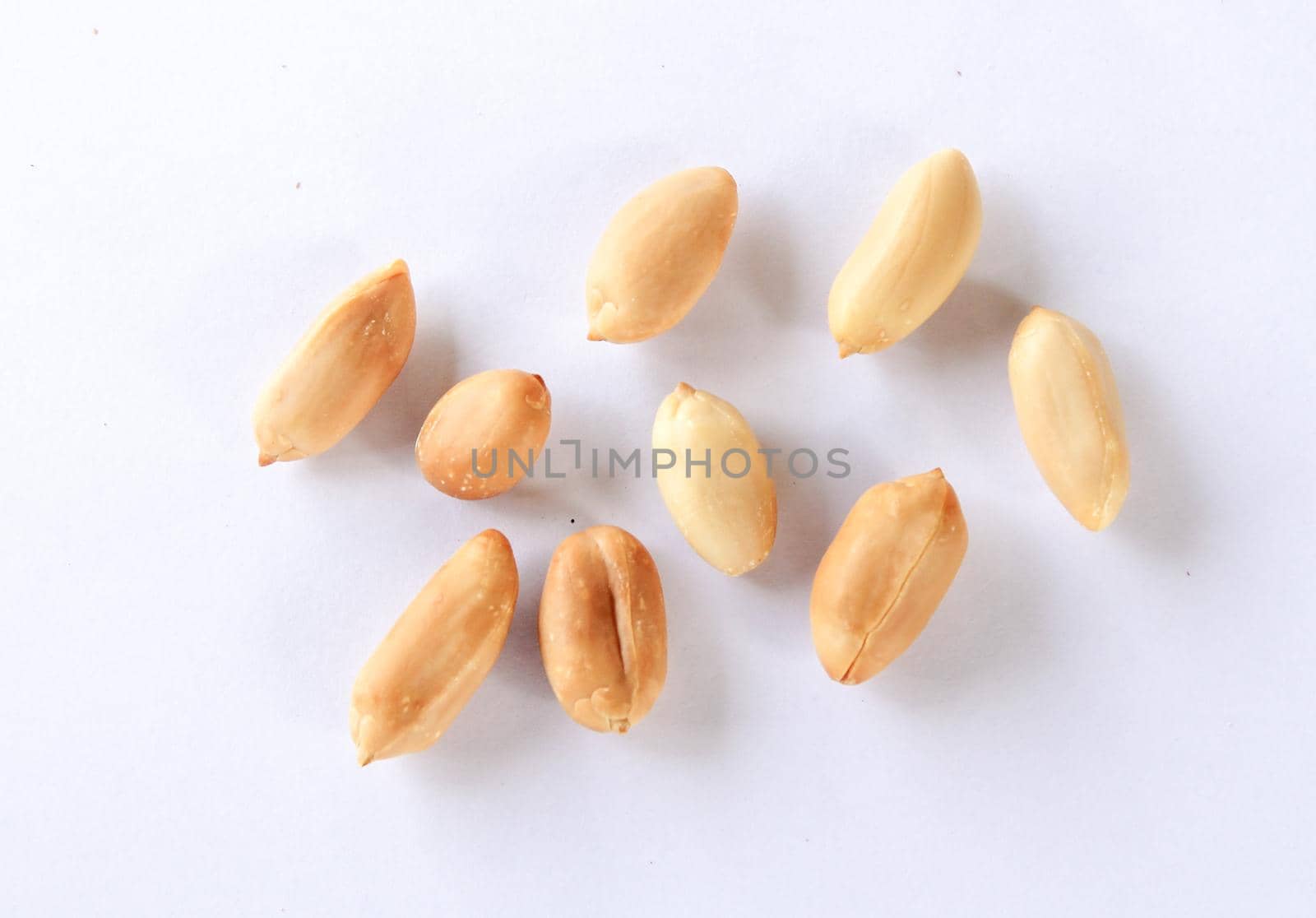 peeled peanuts scattered on a white background