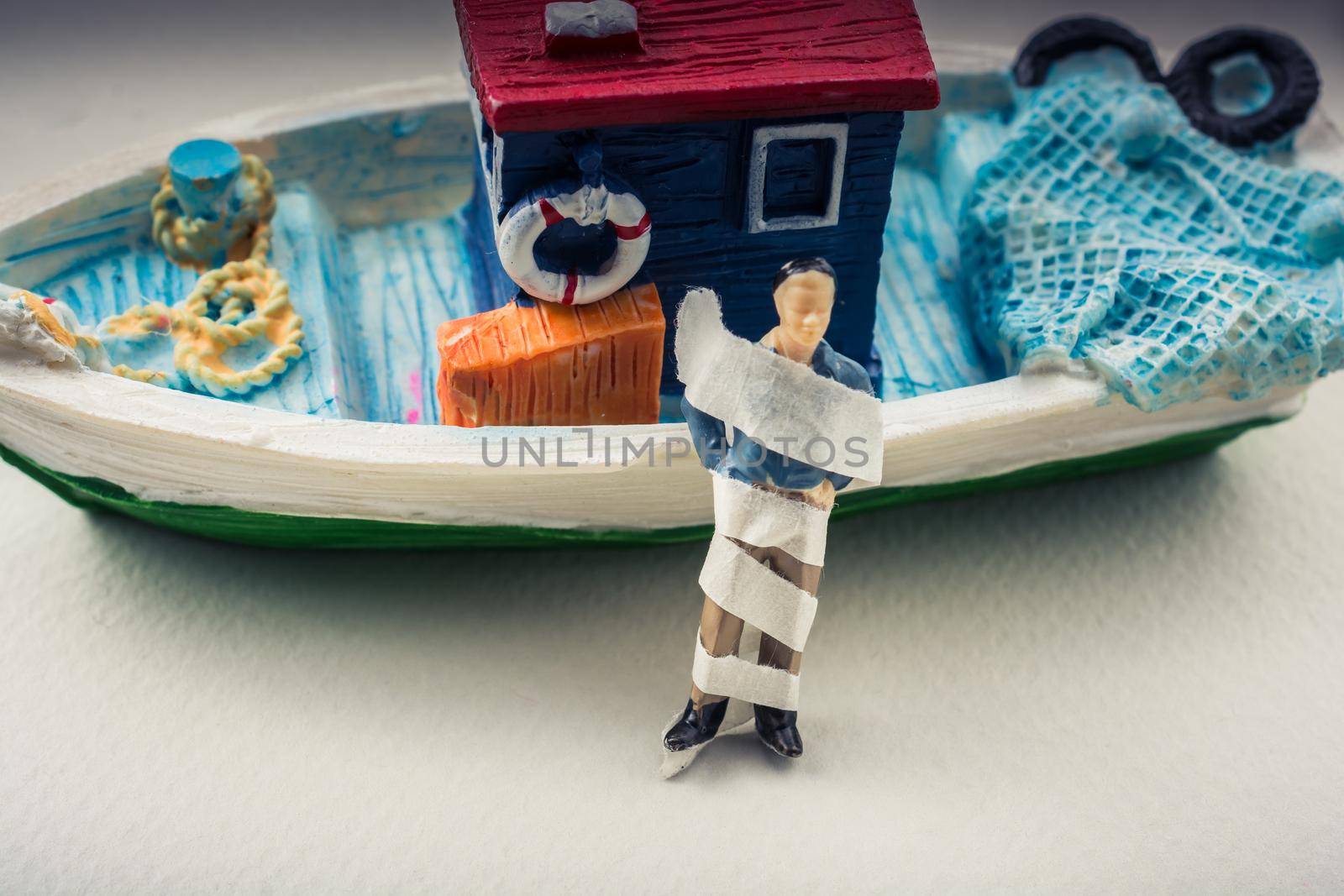 Tiny wrapped figurine of man model beside a model boat