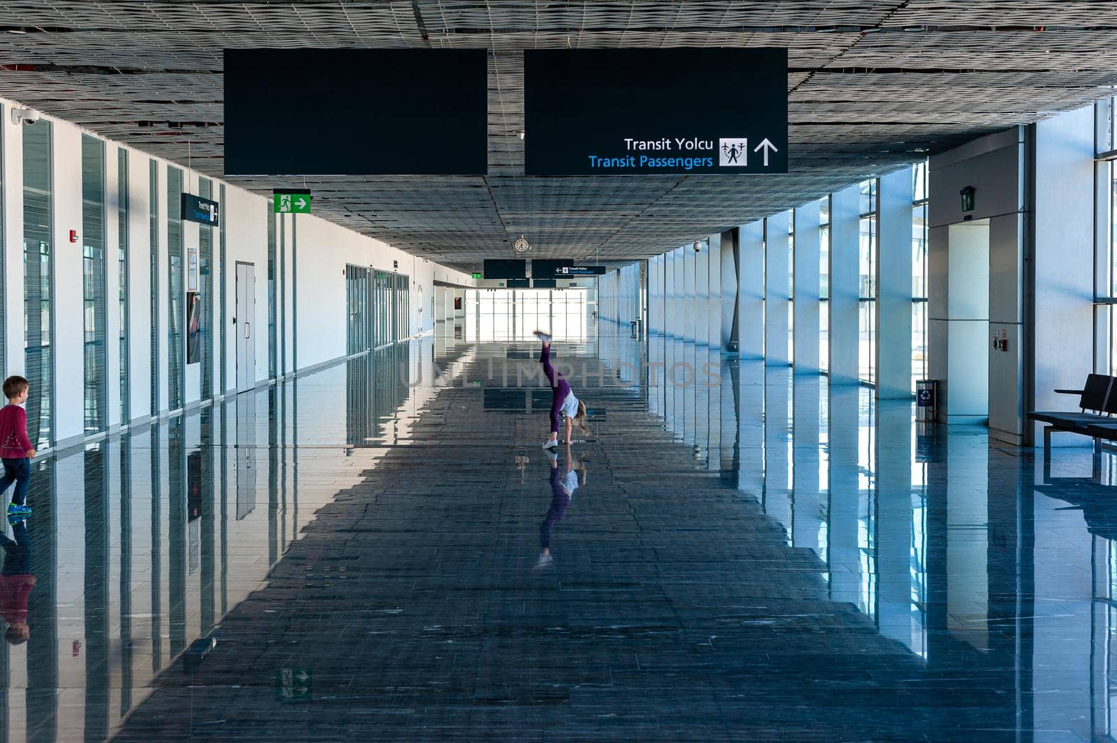 05/26/2019 Bodrum Airport / Milas Mugla Airport. Turkey. Small girl doing cartwheels exercise out of boredom while awaiting for her flight. by Qba