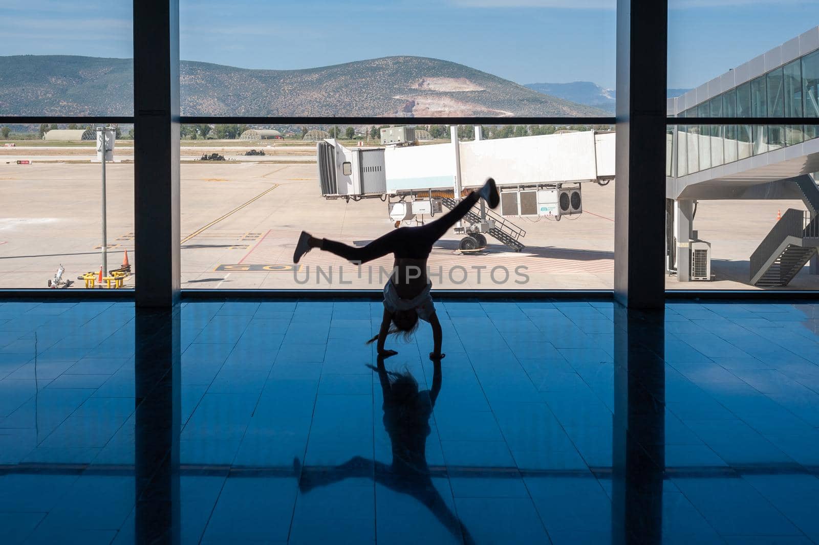 05/26/2019. Bodrum Airport / Milas Mugla Airport. Turkey. Small girl doing cartwheels exercise out of boredom while awaiting for her flight. by Qba
