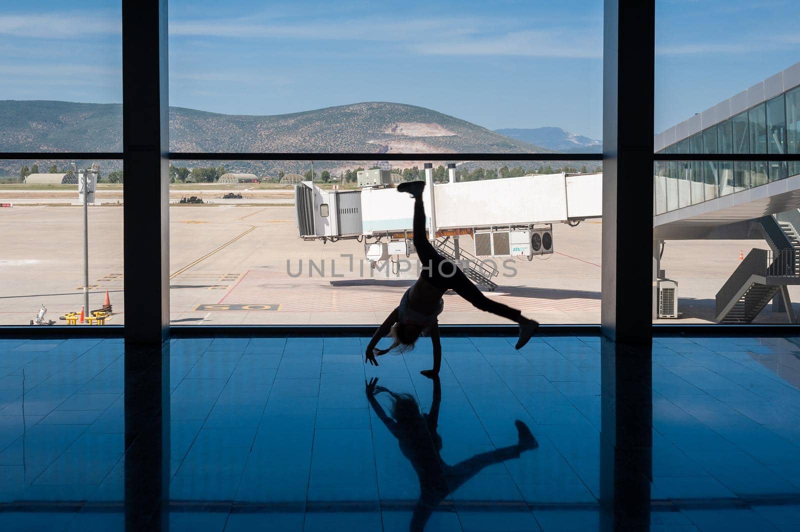 05/26/2019. Bodrum Airport / Milas Mugla Airport. Turkey. Small girl doing cartwheels exercise out of boredom while awaiting for her flight. by Qba