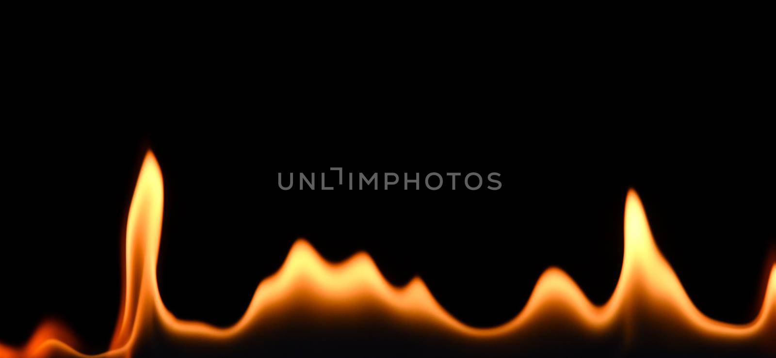 Close up line of fire flames pattern isolated on black background, low angle, side view
