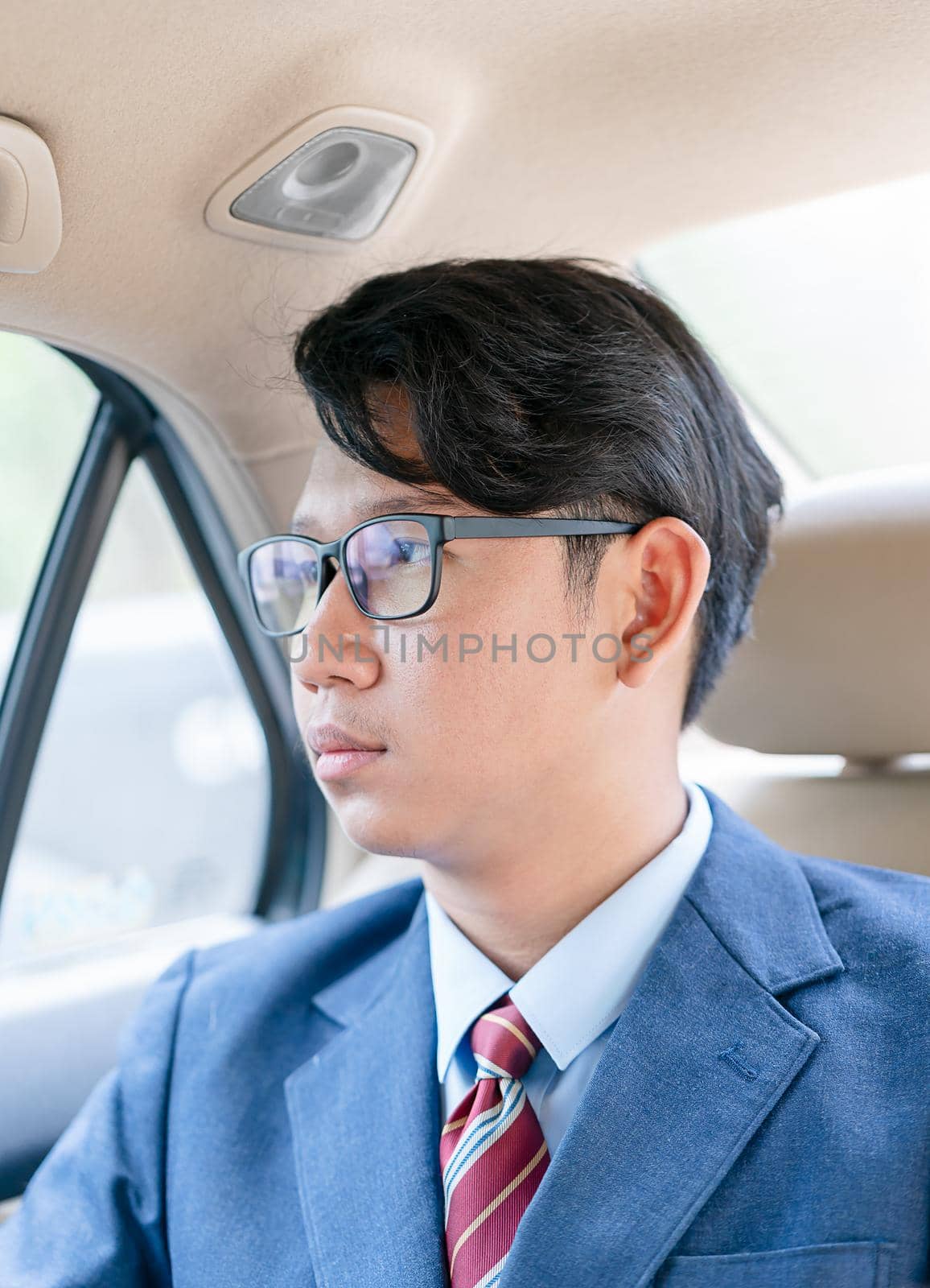Young asian business men portrait in suit working in the backseat of a car