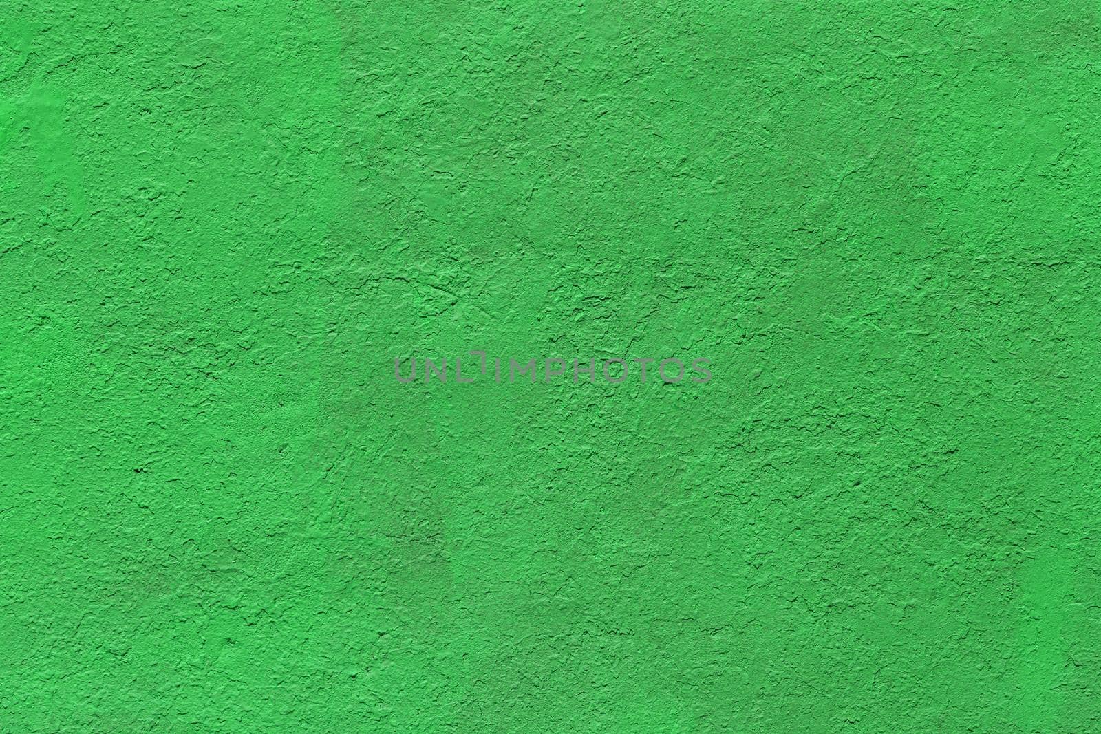 background and texture of flat thick painted matte green surface under direct sunlight - new paint over fragments of old peeled one