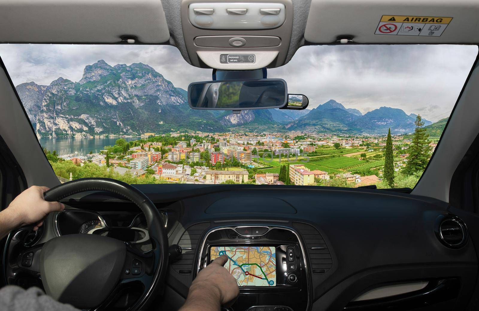 Driving a car while using the touch screen of a GPS navigation system towards Riva del Garda, Northern Lake Garda, Trento, Italy