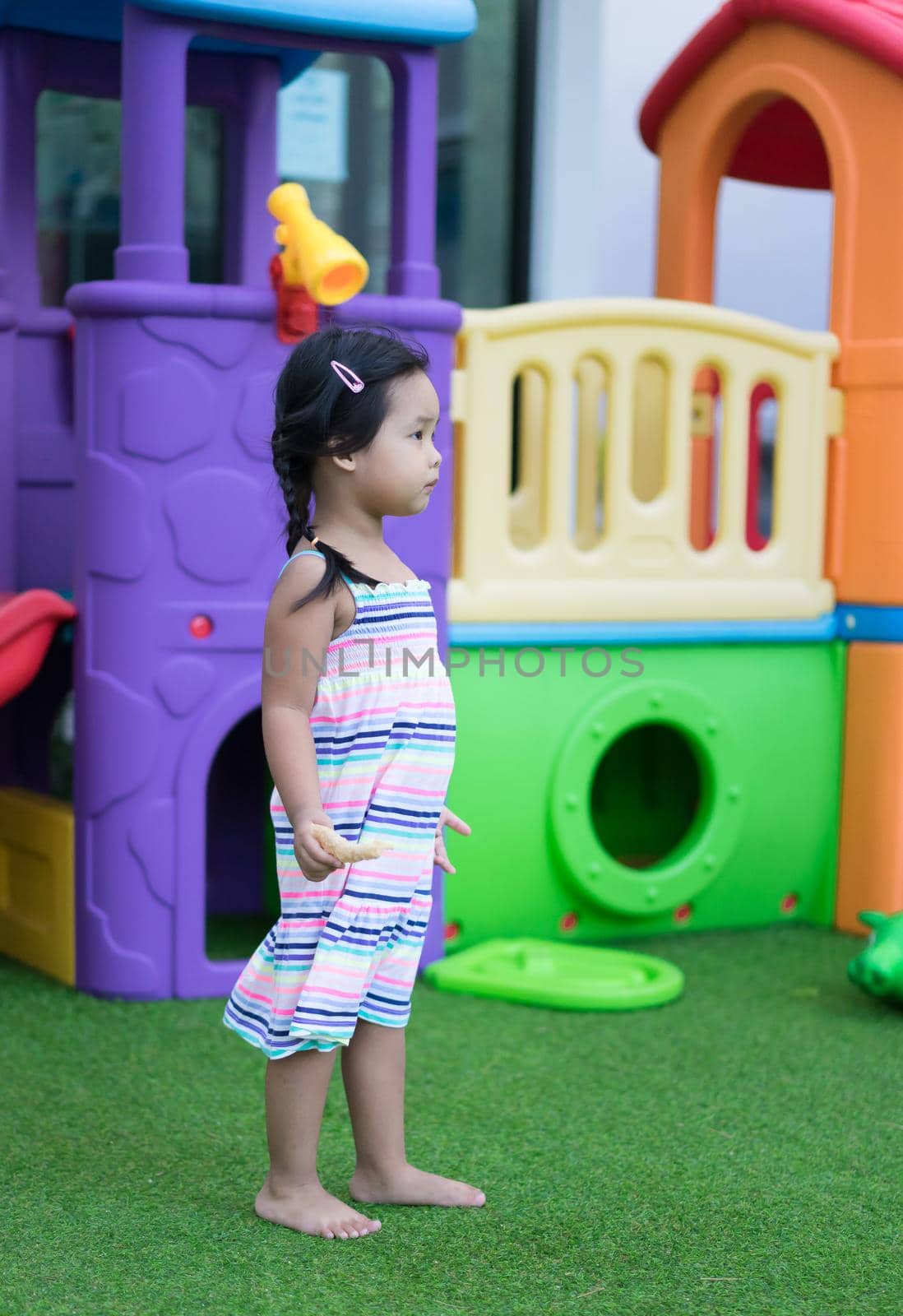 little girl holding a snack in the playground by domonite