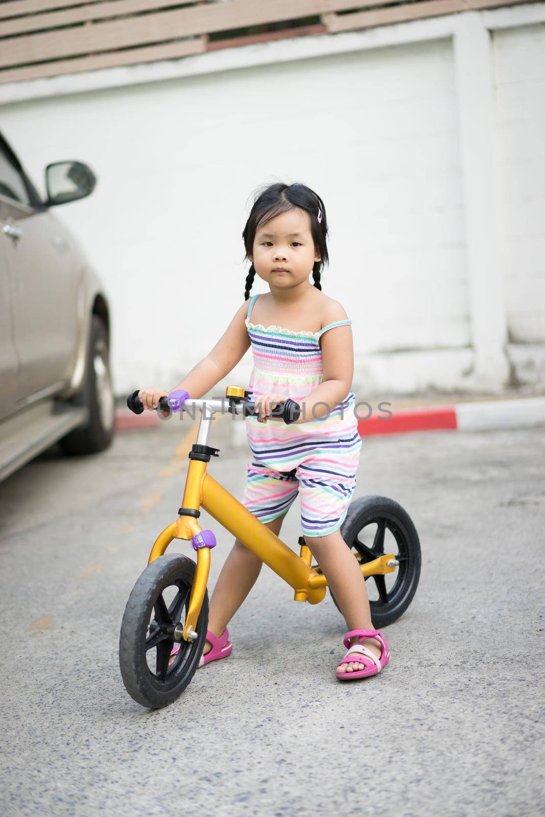 Little girl learns to riding balance bike in car park by domonite