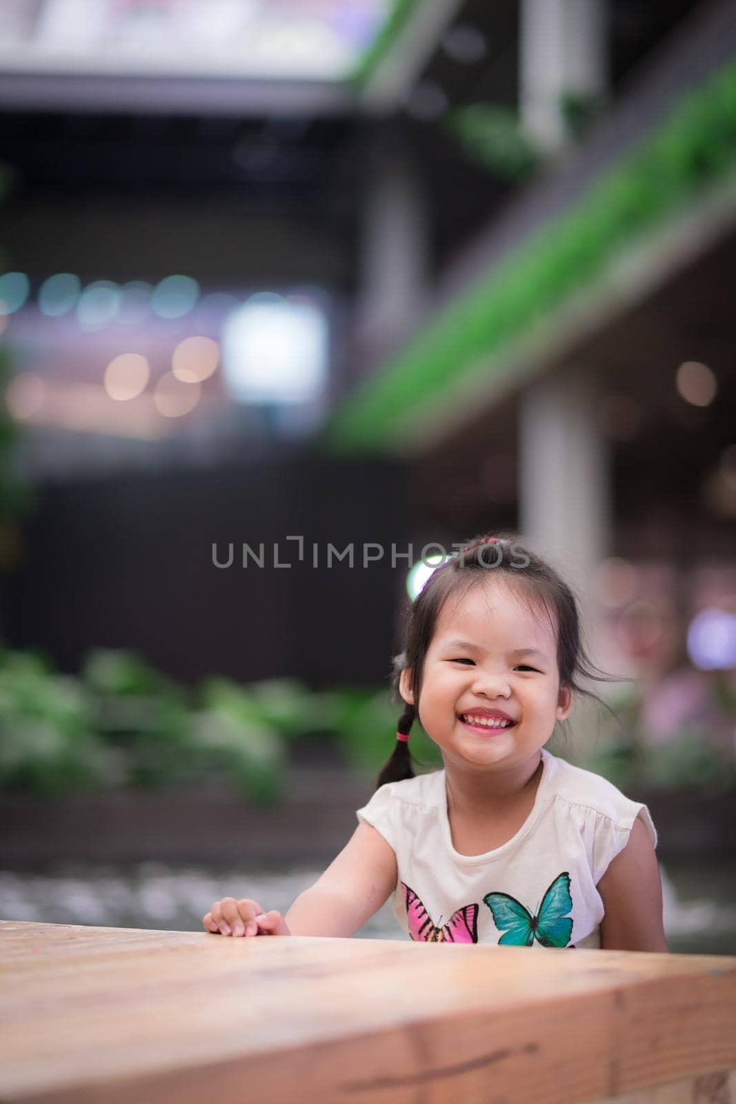 Smiling asian little girl sitting in department store by domonite