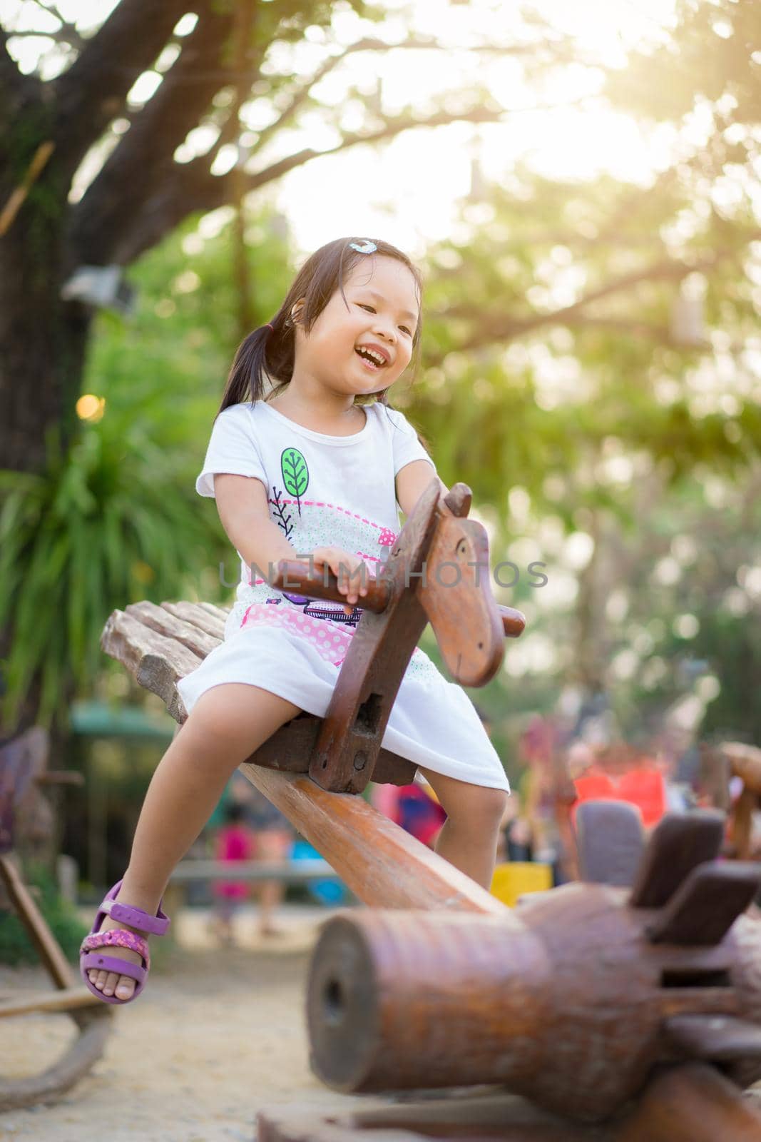 Asian little girl having fun on seesaw at playground