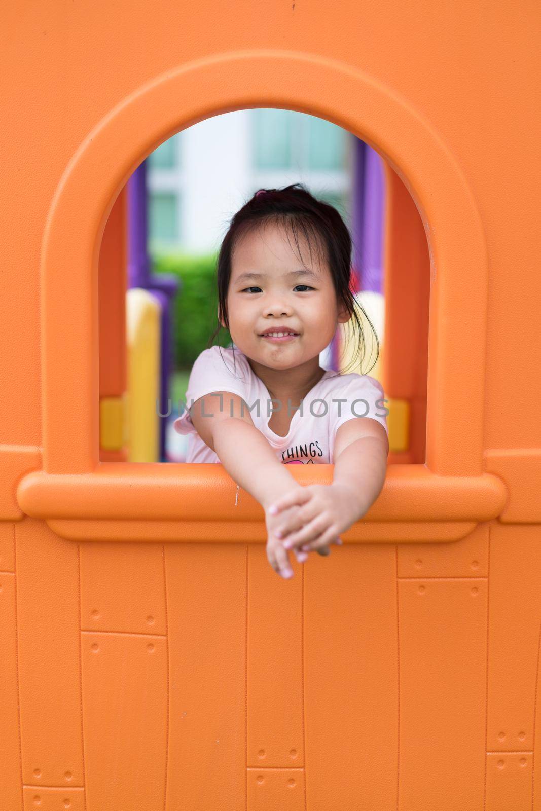 Asian little girl in the window enjoys playing in a children playground