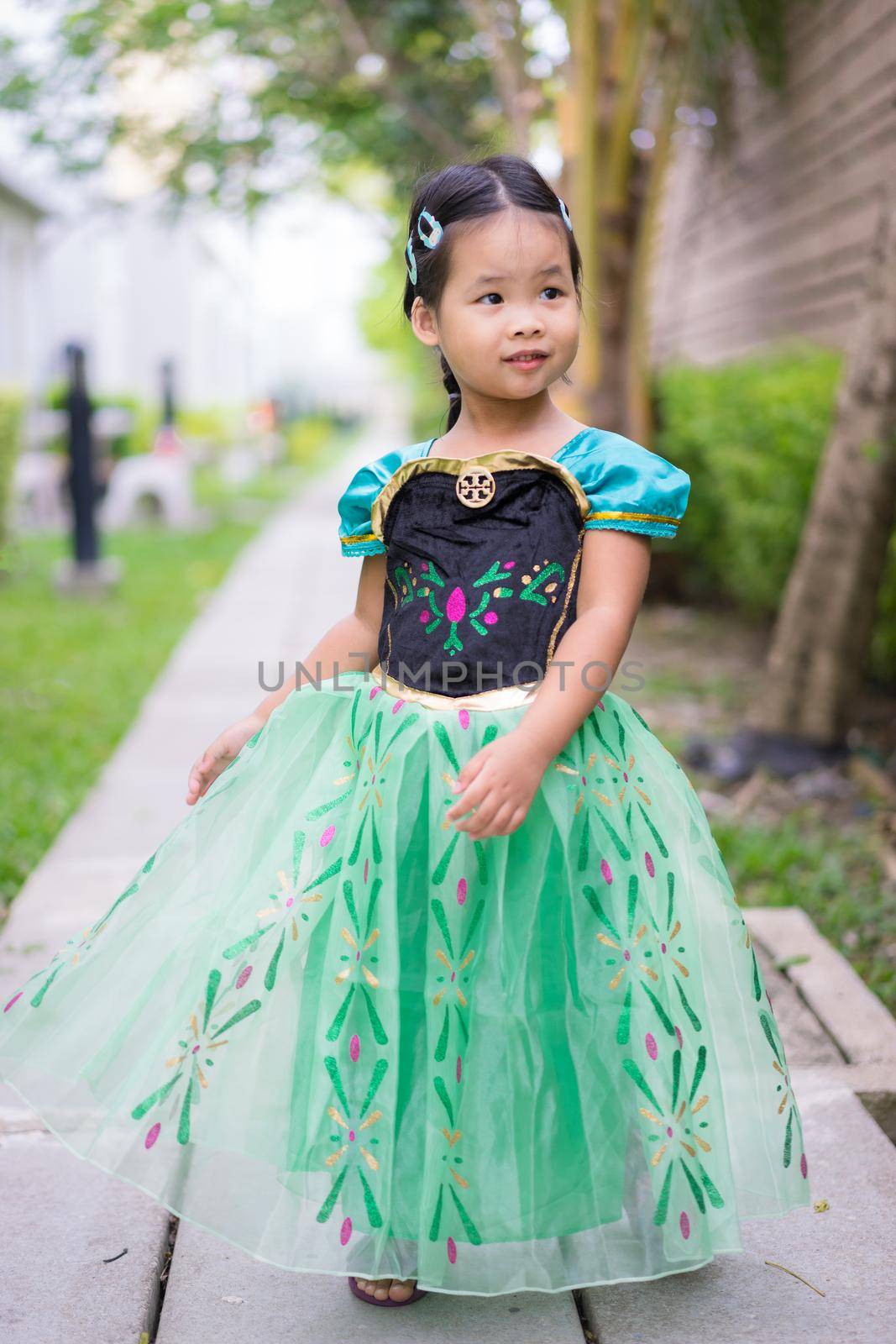 Portrait of cute smiling little girl in princess dress standing in the park by domonite