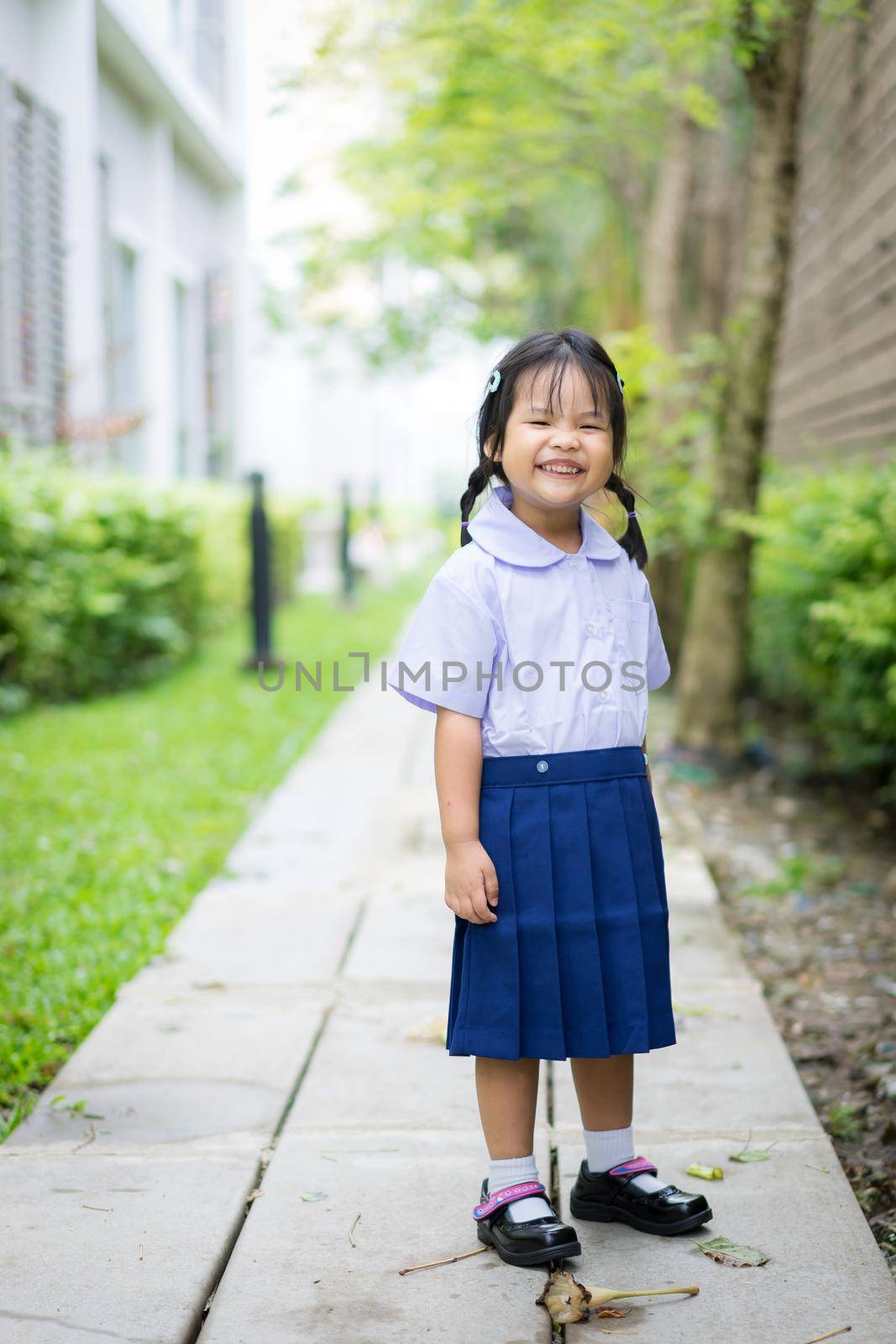 Portrait of happy little girl in Thai school uniform standing in the park and copy space,ready back to school by domonite