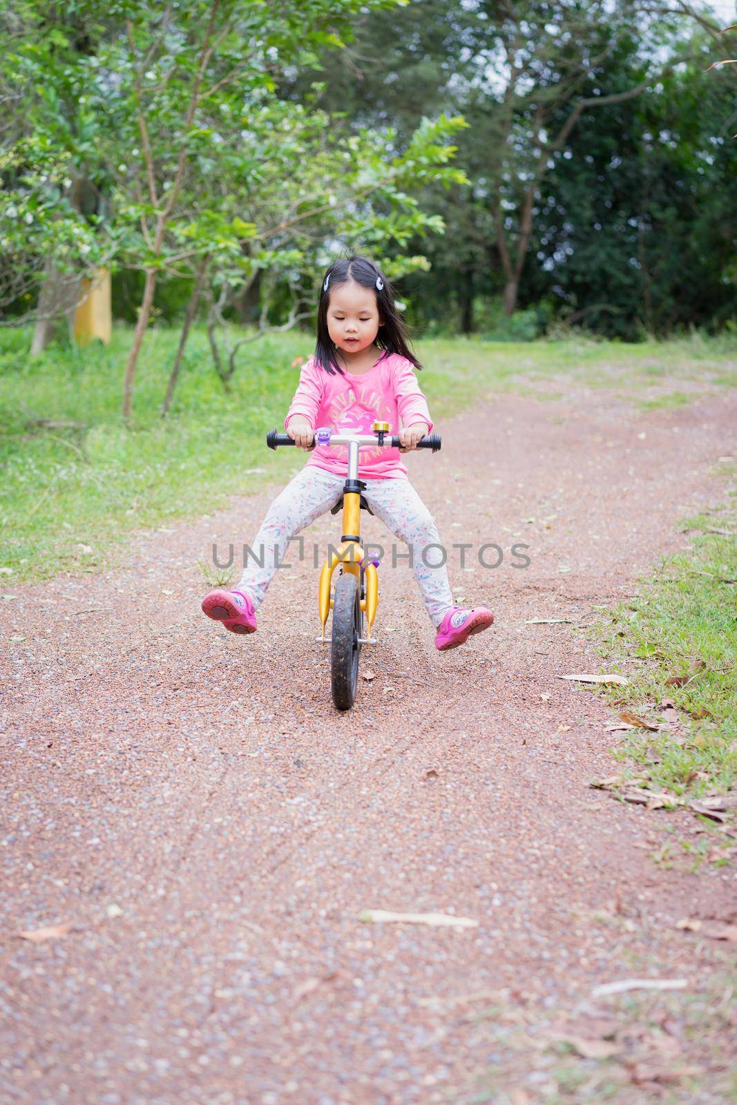 Little girl learns to riding balance bike on slope in the park by domonite