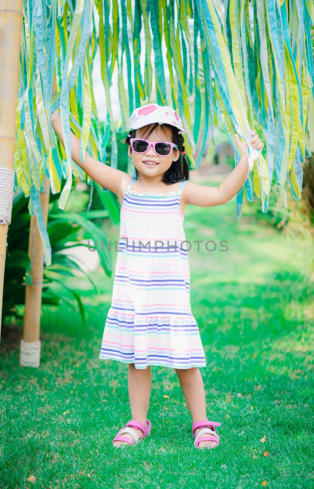 portrait of cute asian little girl wear sunglasses and hat in the park