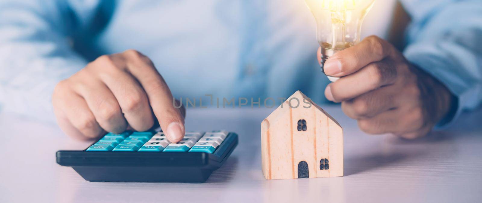 Hand of businessman planning and calculate expense and mortgage with calculator and home on desk, insurance and budget of residential, examining of loan and residence, business and property concept.