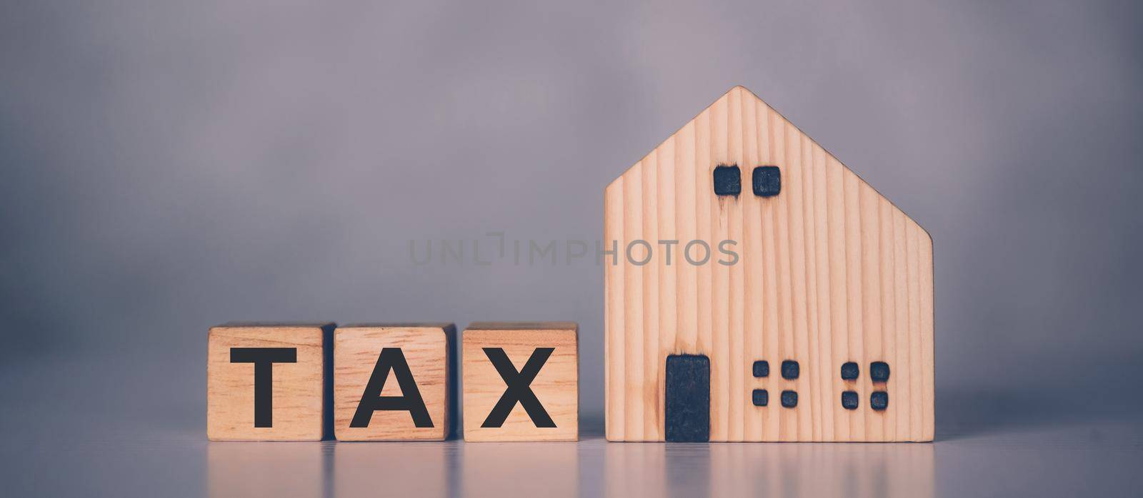 Wooden block cube with TAX word and home model, real estate and property about finance, planning with financial, investment about residential and tax, budget and taxation, business concept. by nnudoo
