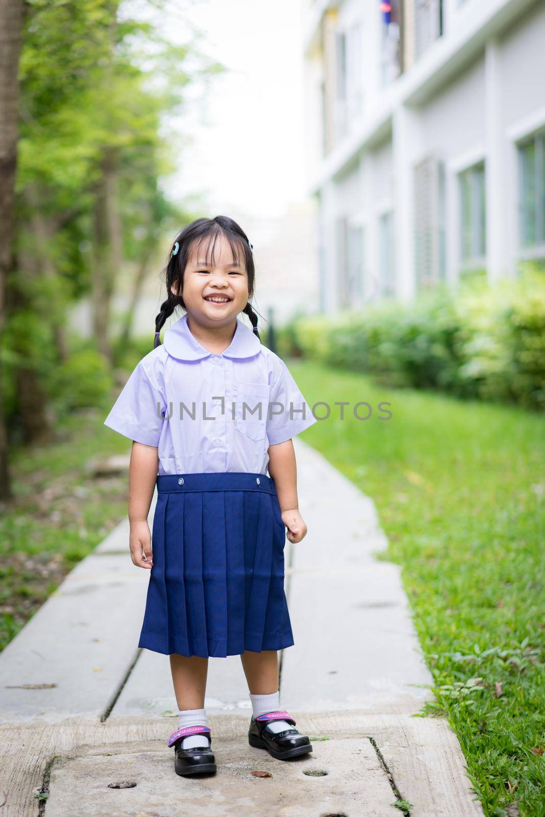 Portrait of happy little girl in Thai school uniform standing in the park and copy space,ready back to school