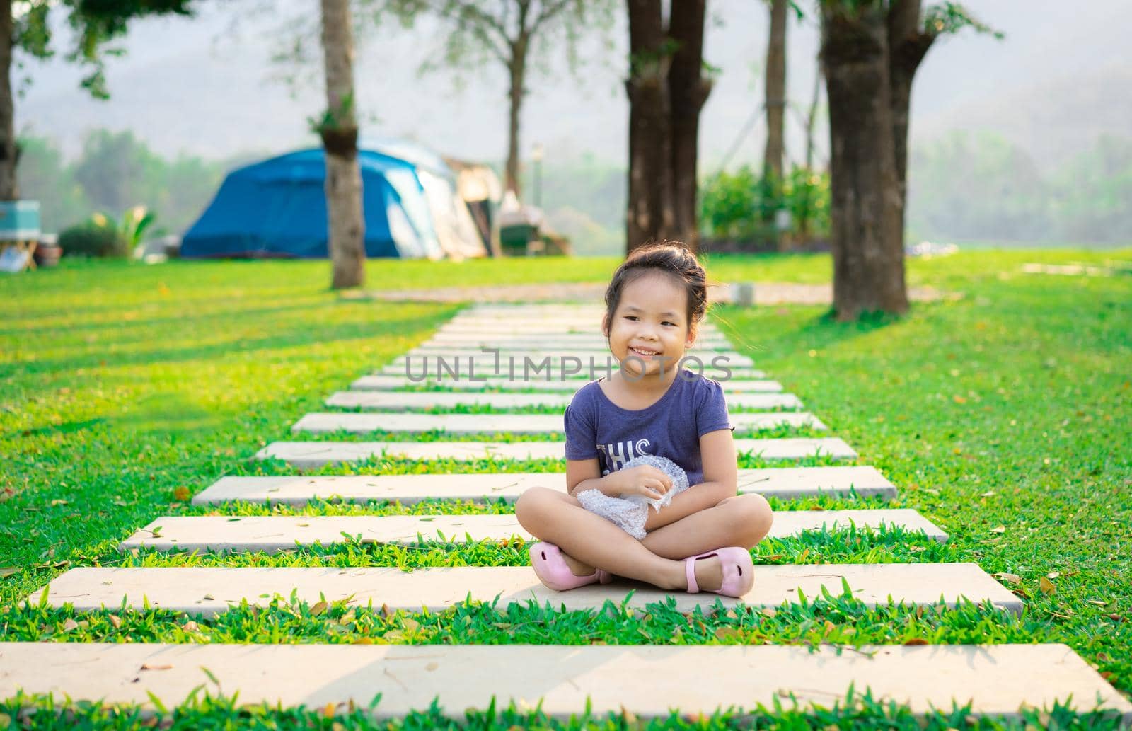 little girl sitting on footpath while going camping by domonite
